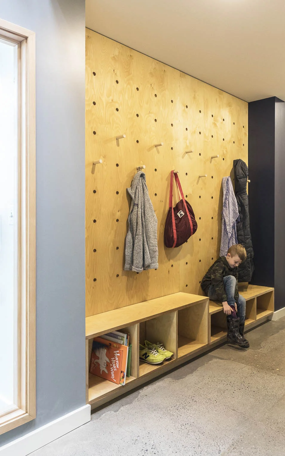 An oversized pegboard, bench and cubbies create a place for boots, coats and bags. Logo below by Caitlin Dale.