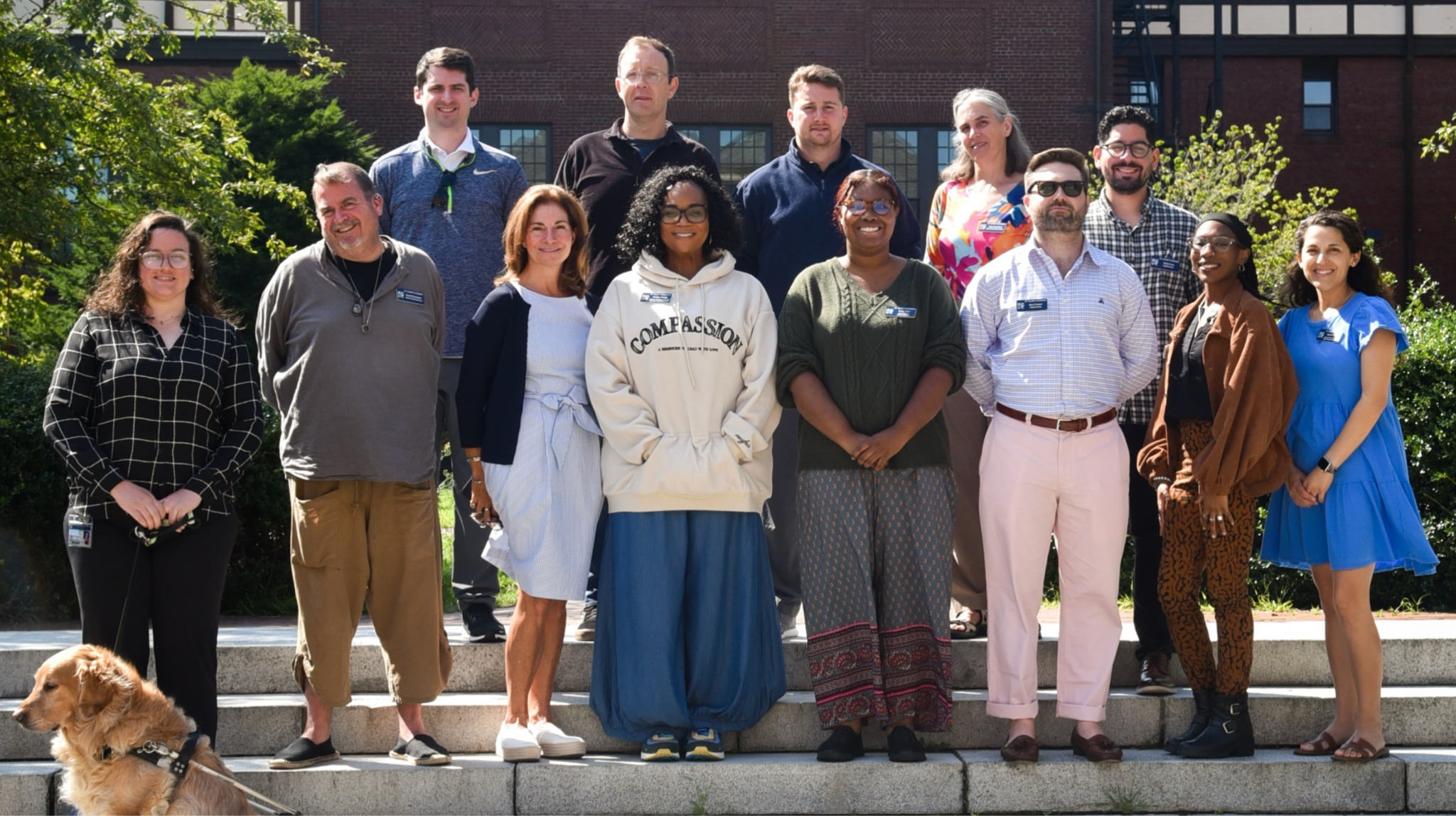 New faculty members stand together outside a campus building.