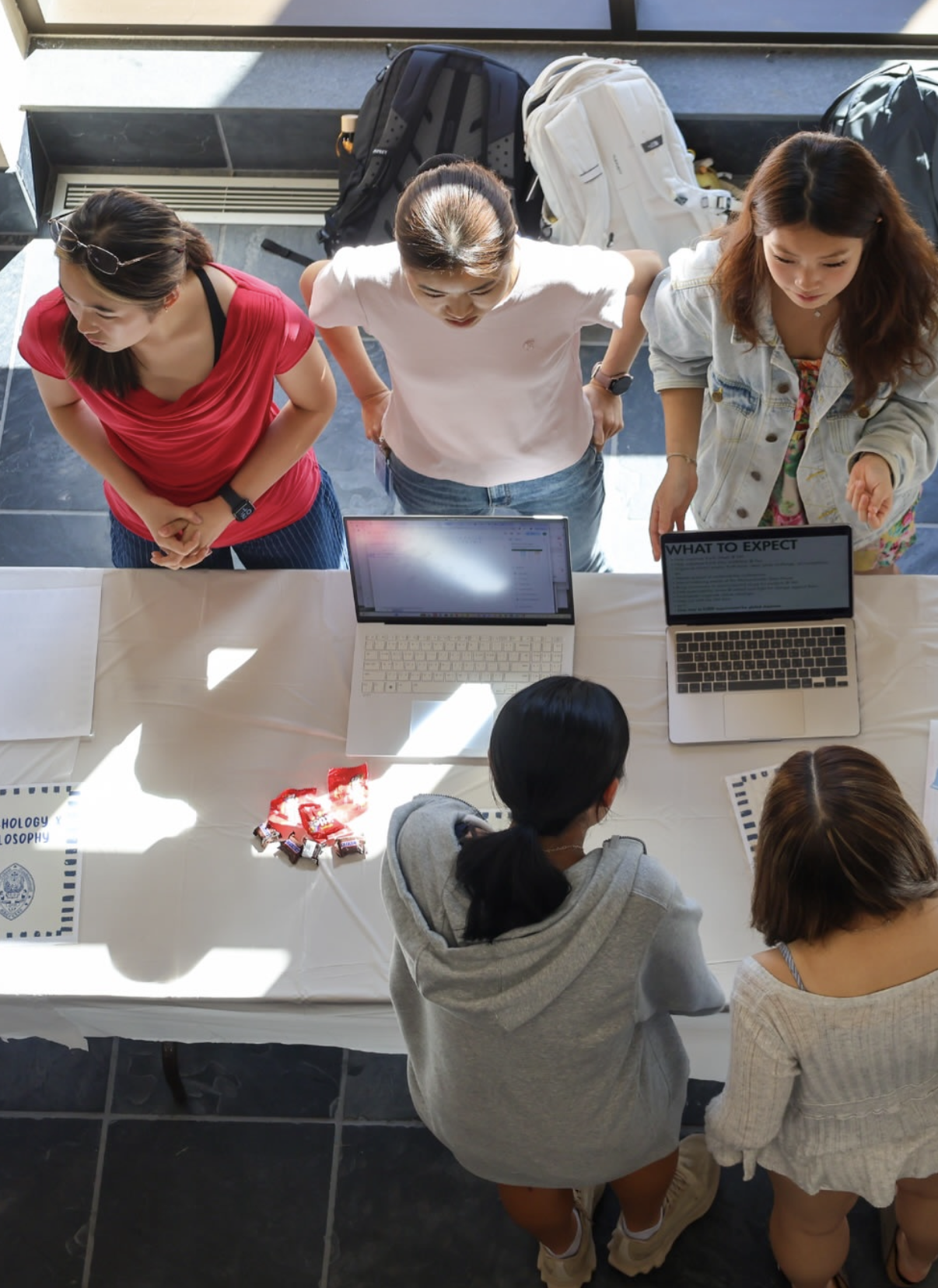 Students talk at a Community Life Fair table with laptops and club information.