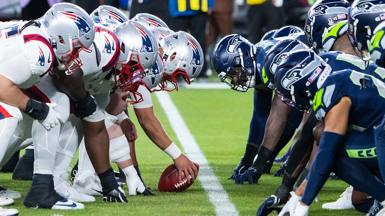 New England Patriots and Seattle Seahawks players face each other at the line of scrimmage.
