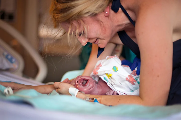 The midwife passes her baby between her legs and lays him gently on the bed. He's finally here. The one they've been dreaming of. The next few images show what's known as "the birth pause." I had never seen it before as many providers place the child directly on mom's chest. But when undisturbed, many women take a moment, take some breaths and look over their baby before bringing him in close.