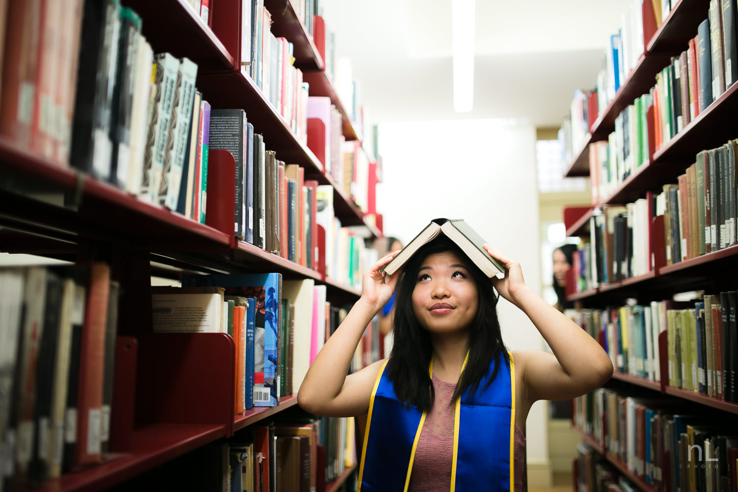 UCLA graduation portraits inside Powell Library with books