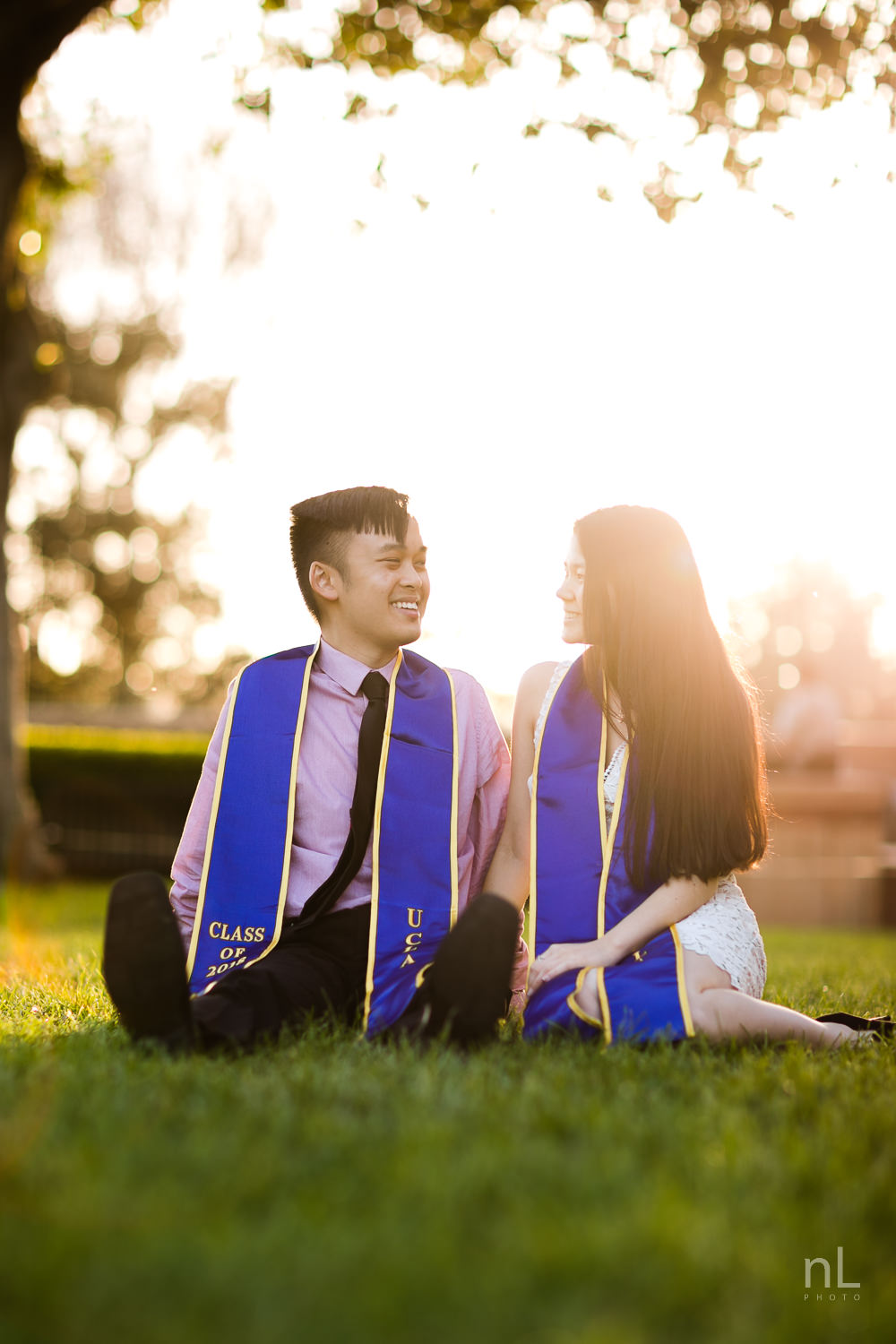 los-angeles-ucla-senior-graduation-portraits-couple-with-sashes-sitting-in-grass-sunset