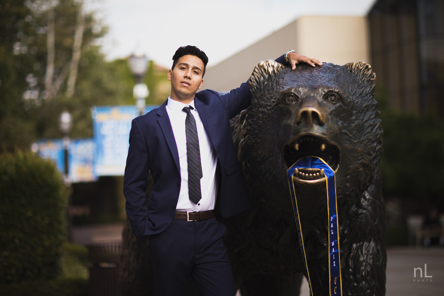 UCLA Class of 2019 graduate wearing suit and graduation sash at Bruin Bear.