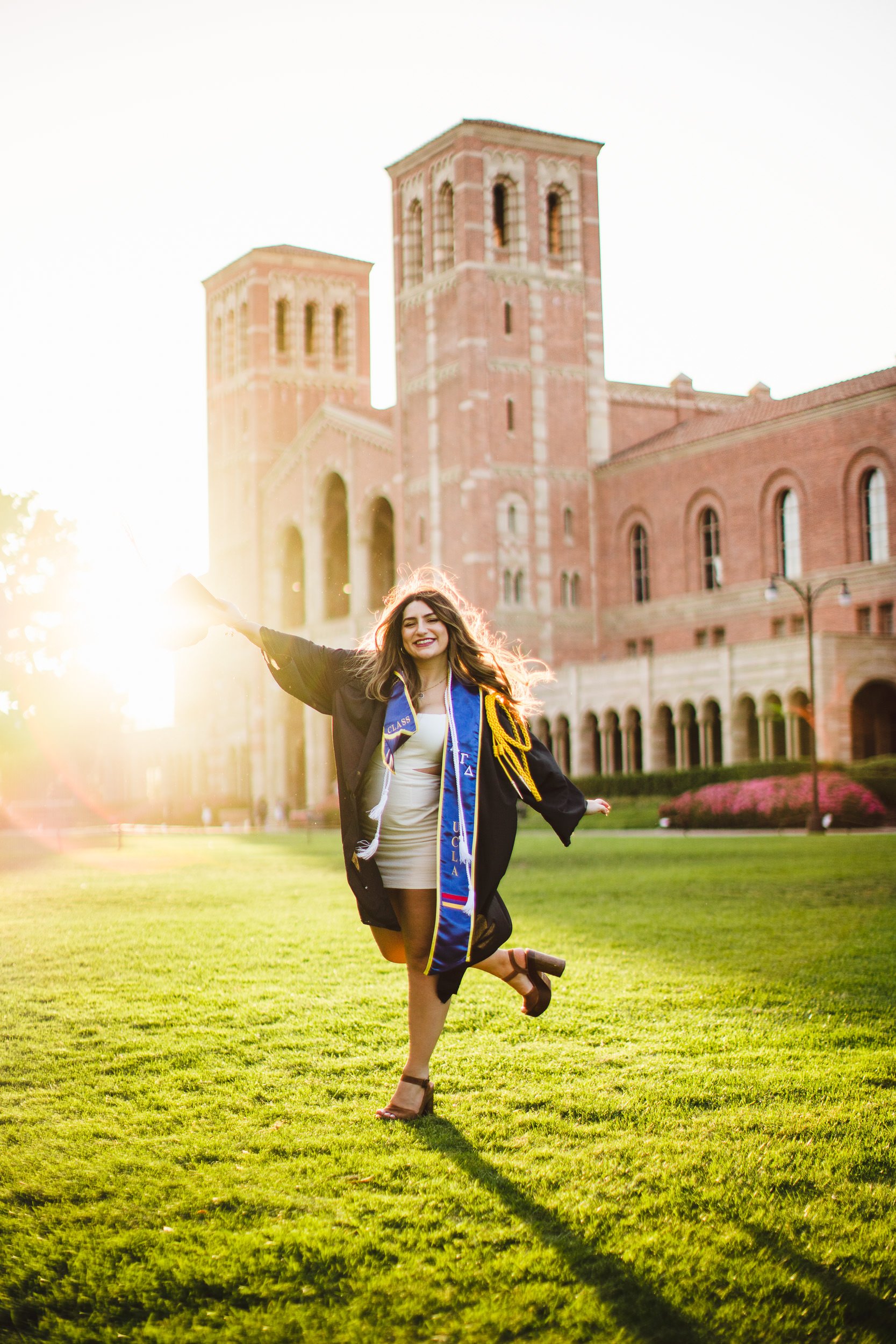 Action graduation portraits, UCLA graduate in bright sunset backlight at Royce Hall. Los Angeles, CA