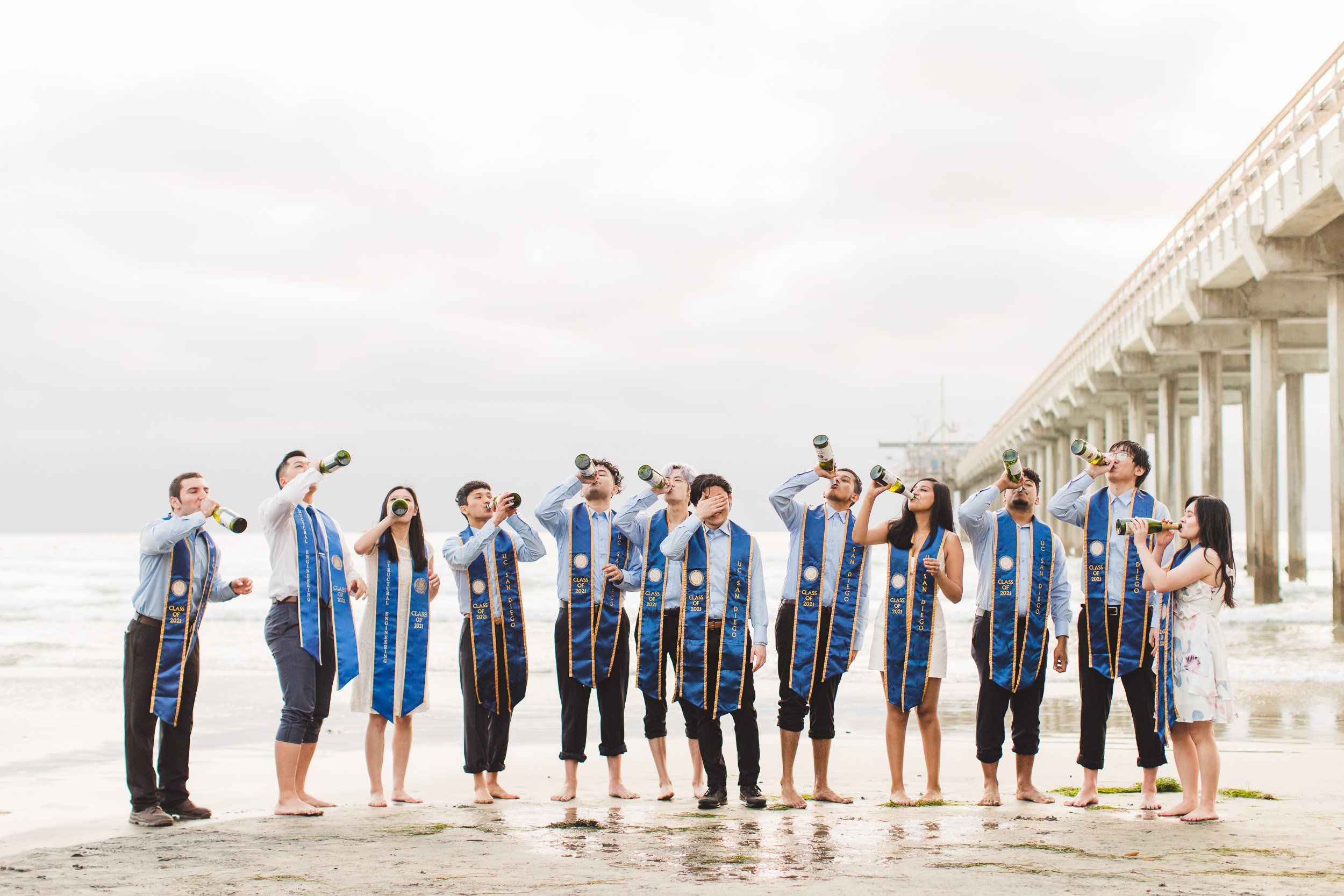 Graduation Portraits for large groups at the beach, action shot of popping champagne bottles and funny moment captured. Los Angeles, CA