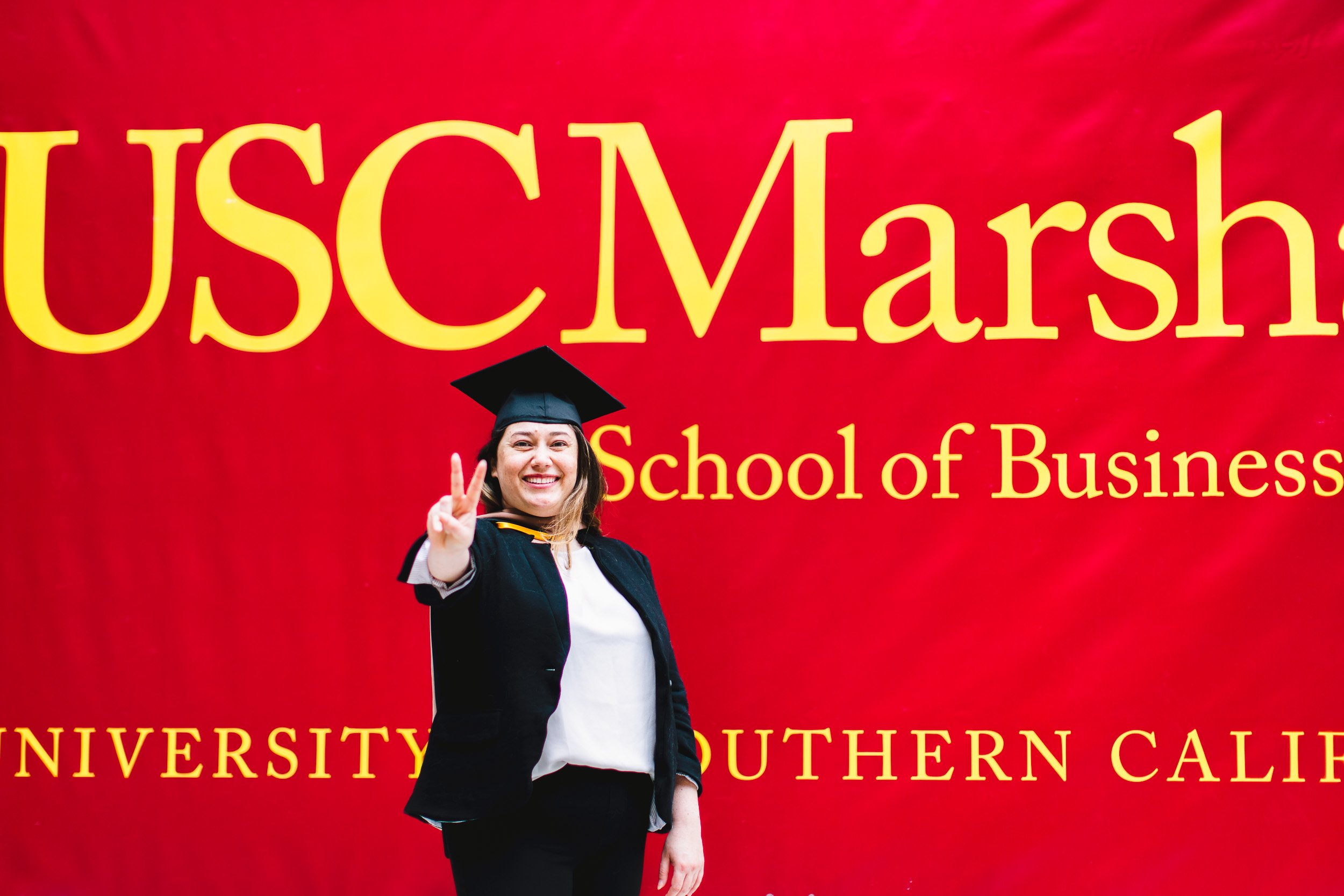 USC Marshall Graduation Portraits of graduate in front of large School of Business banner. Los Angeles, CA