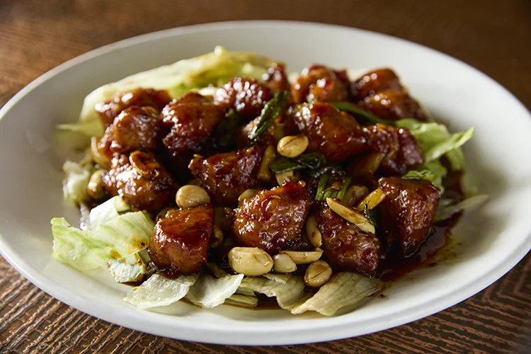 The Sichuan Gon Bao Pork, cubed pork fried and stirred in a sichuan spicy sauce topped with peanuts over a bed of lettuce and topped with peanuts, a delicious classic served at Royal China