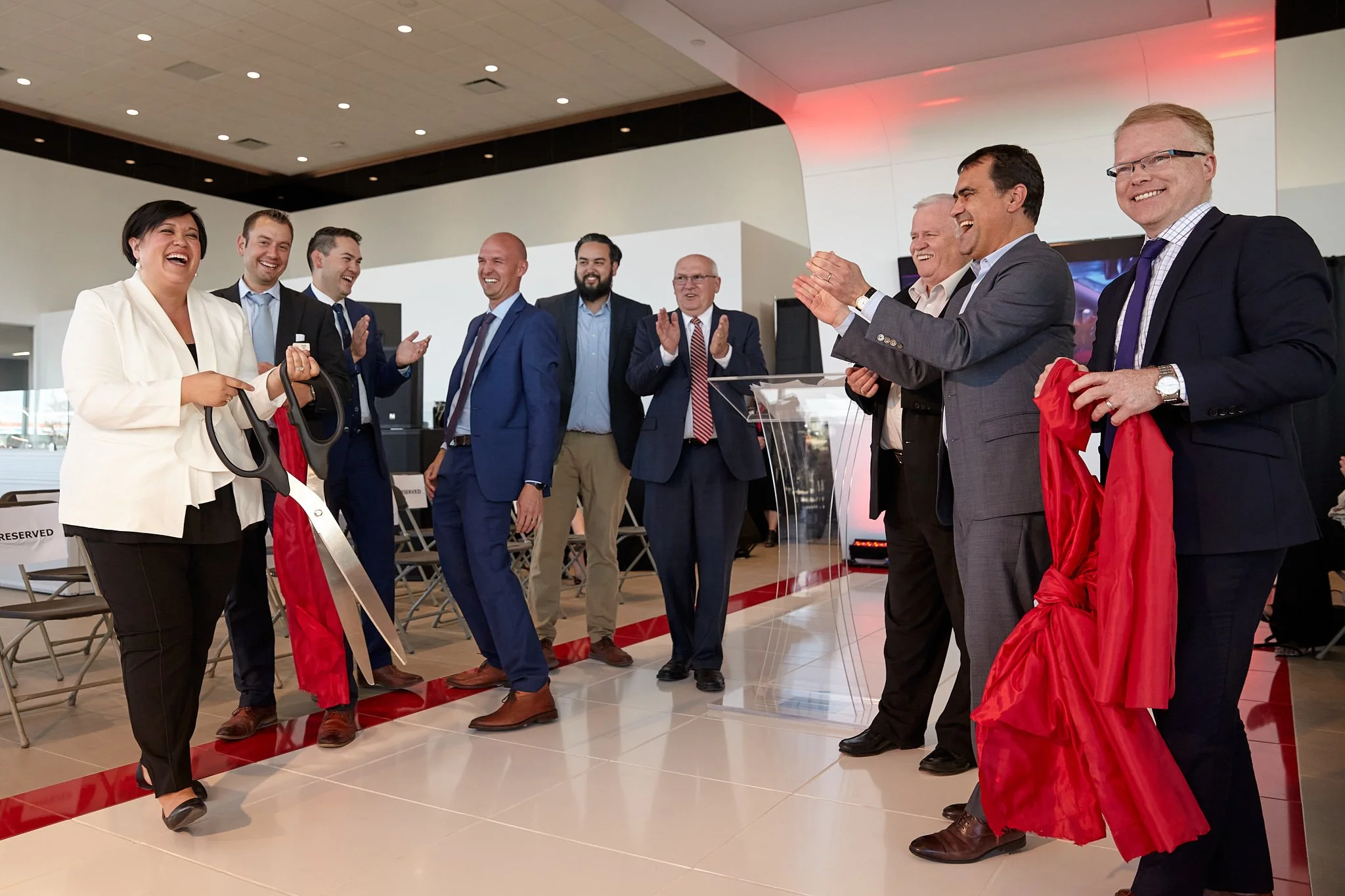 Ribbon-cutting ceremony at the opening of Country Hills Nissan in Calgary – big smiles and giant scissors in action. Corporate event captured by Stance Creative photography.