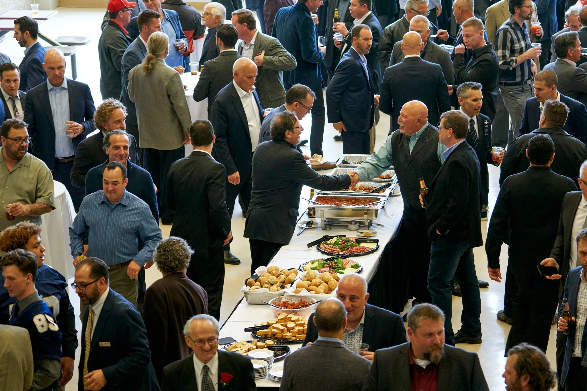 Large crowd of Italian Sportsman mingling around buffet tables at their annual event in Calgary. Busy, energetic scene captured by Stance Creative event photographer.