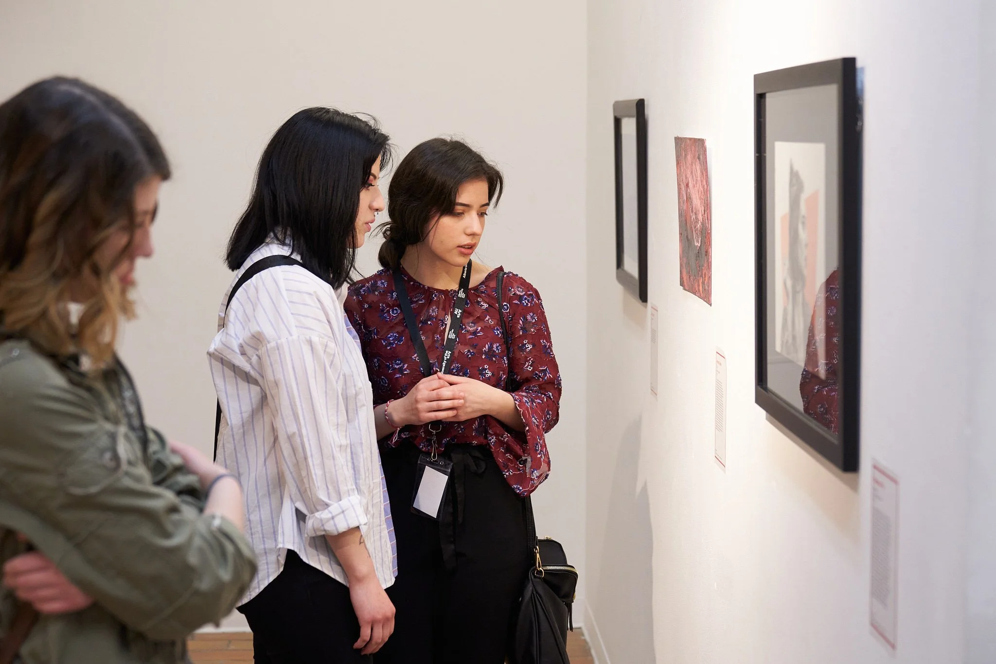 Art enthusiasts admiring student works at AU Arts Show-off gallery exhibition opening in Calgary. Intimate cultural moment photographed by Stance Creative.