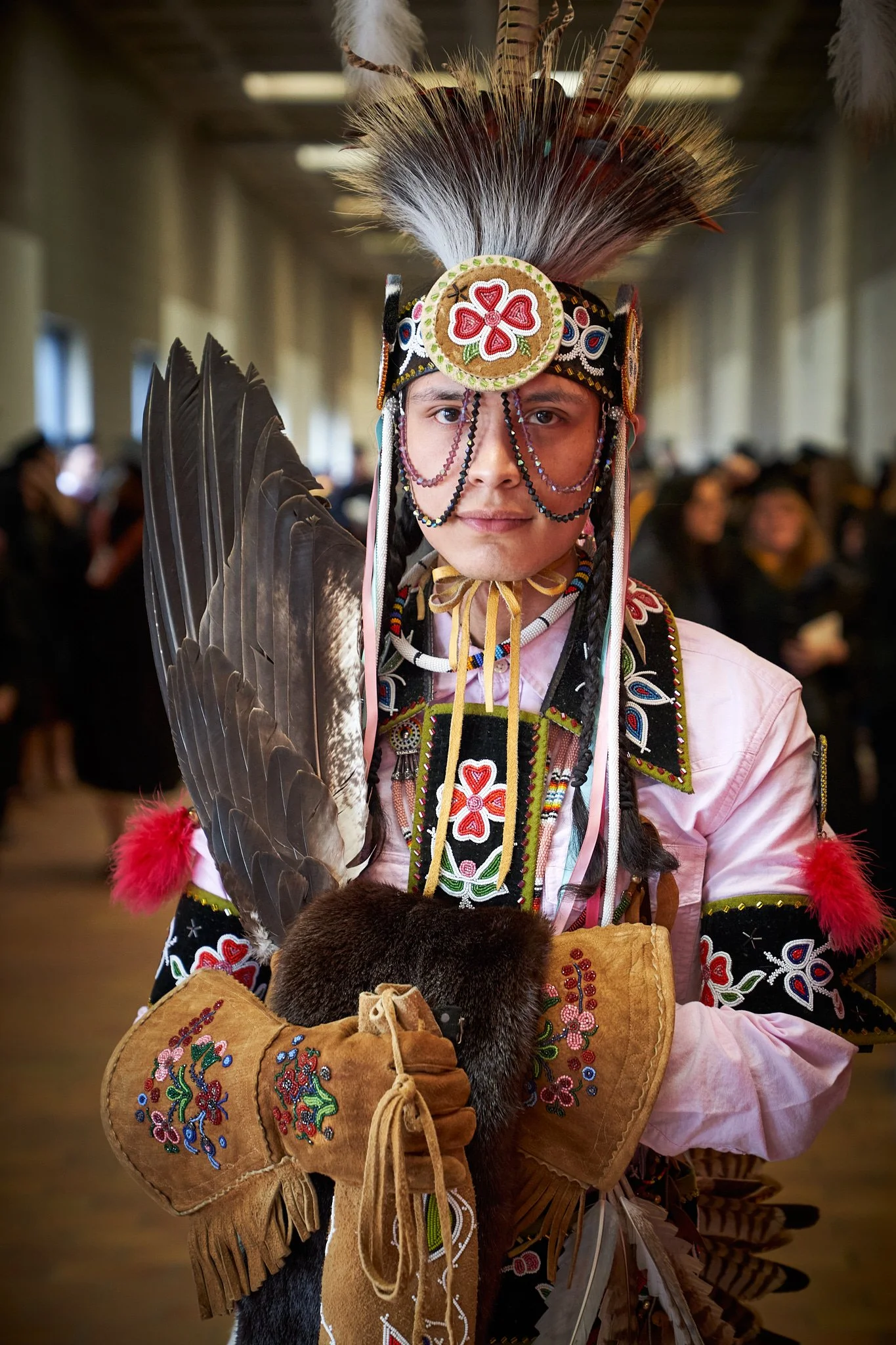 Indigenous student in full regalia with elaborate feathered headdress, beaded outfit, and fur accents ready for graduation at the AU Arts Convocation Ceremony. Event Photography Portrait by Stance Creative.