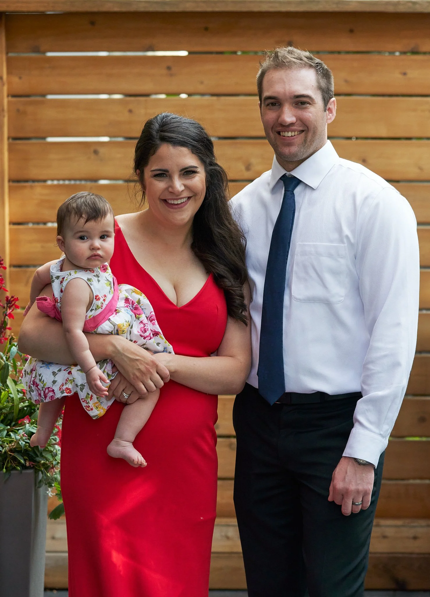 A happy couple beaming with their infant daughter. Calgary family portrait session outdoors. Joyful, natural-light moment by Stance Creative.