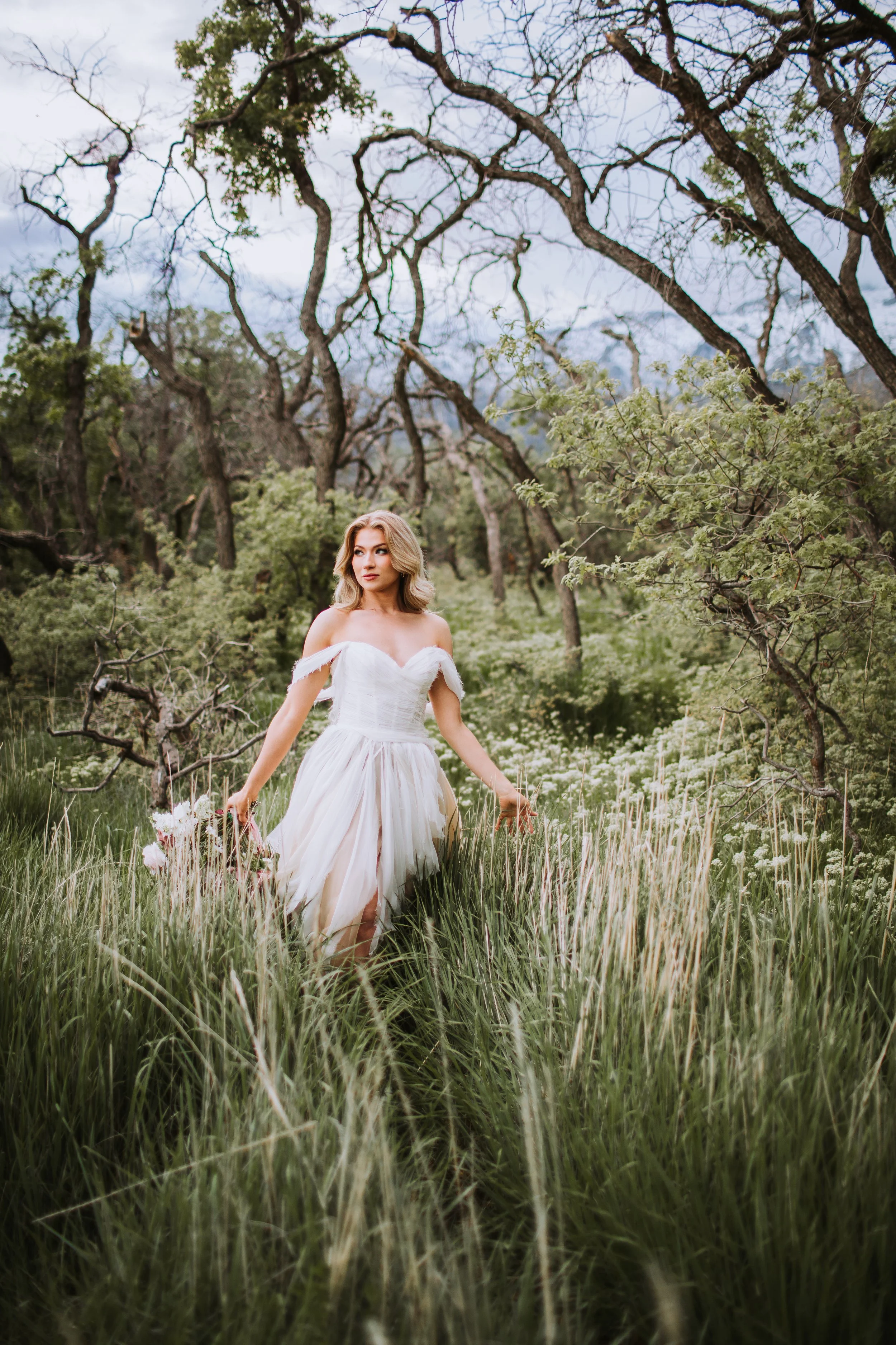 Claire blush wedding dress flowing in wildflower meadow