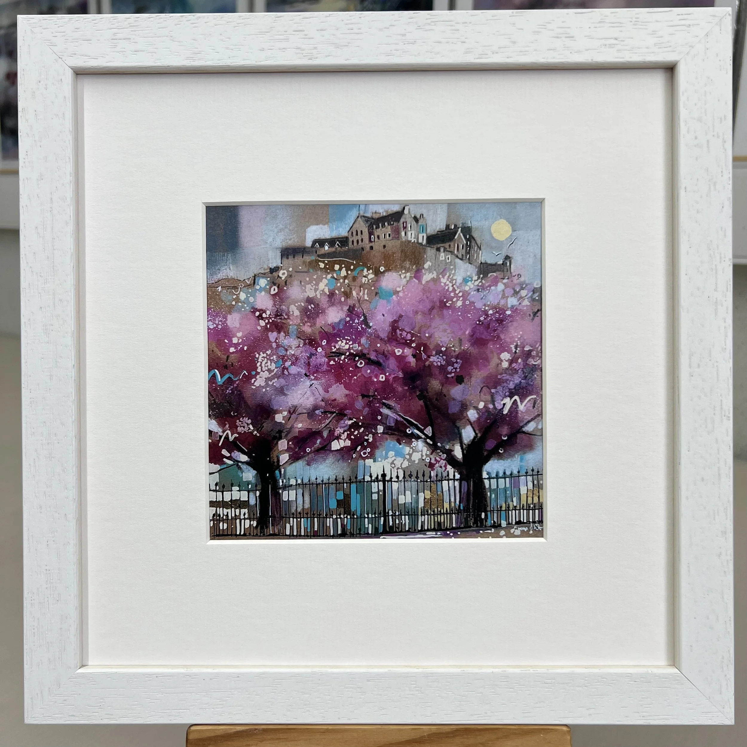Edinburgh in Bloom framed art card featuring Edinburgh Castle above blossom trees in Princes Street Gardens, Scotland. Framed white single mount.