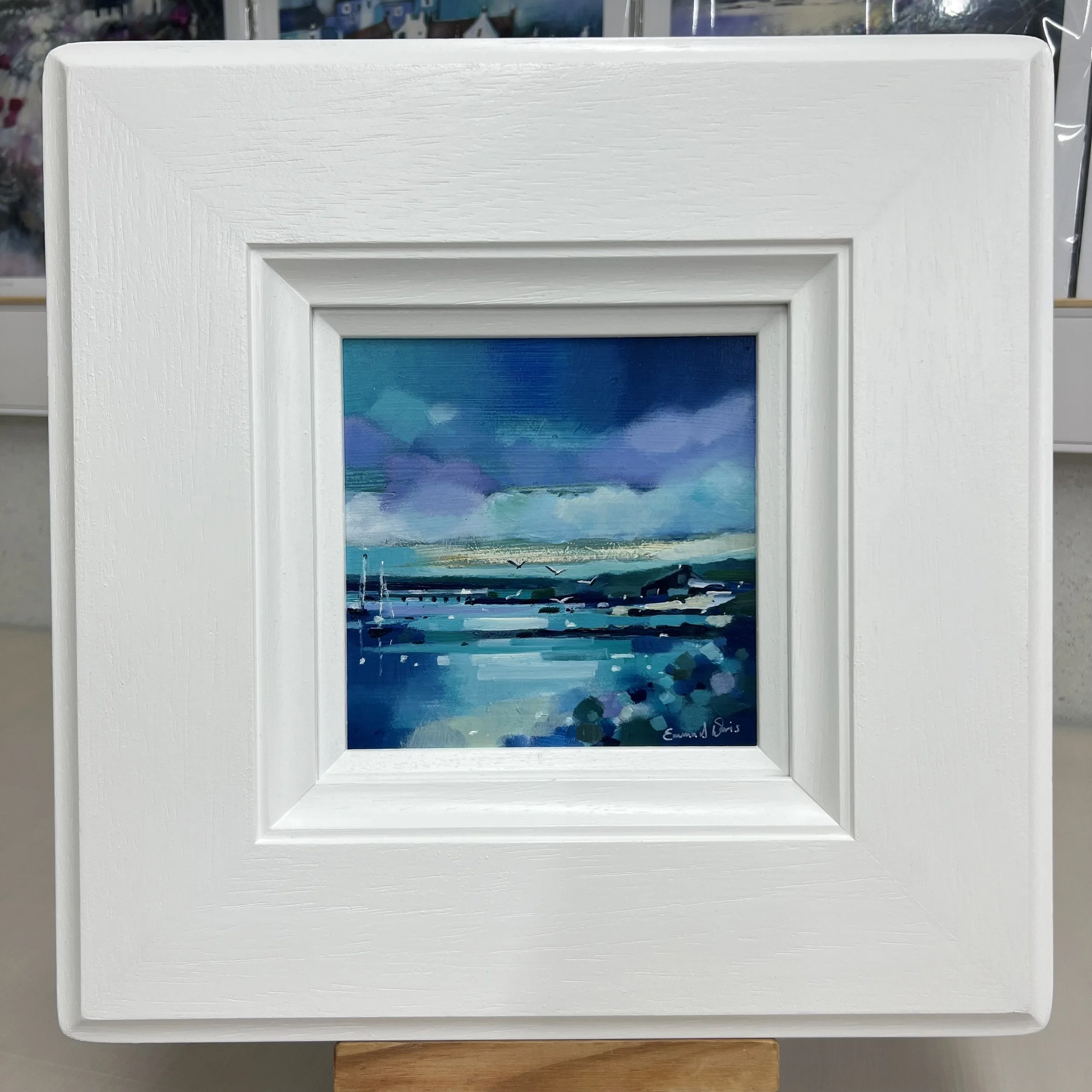 Original oil painting of a white boathouse on the Isle of Gigha surrounded by wildflowers and coastal scenery by Scottish artist Emma S Davis. Framed view.