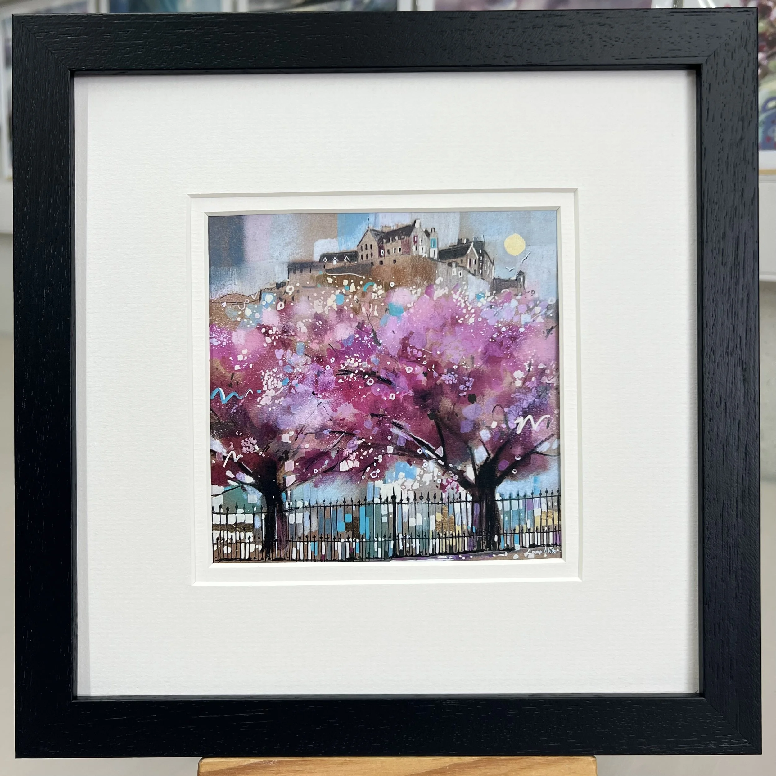 Edinburgh in Bloom framed art card featuring Edinburgh Castle above blossom trees in Princes Street Gardens, Scotland. Framed black double mount.