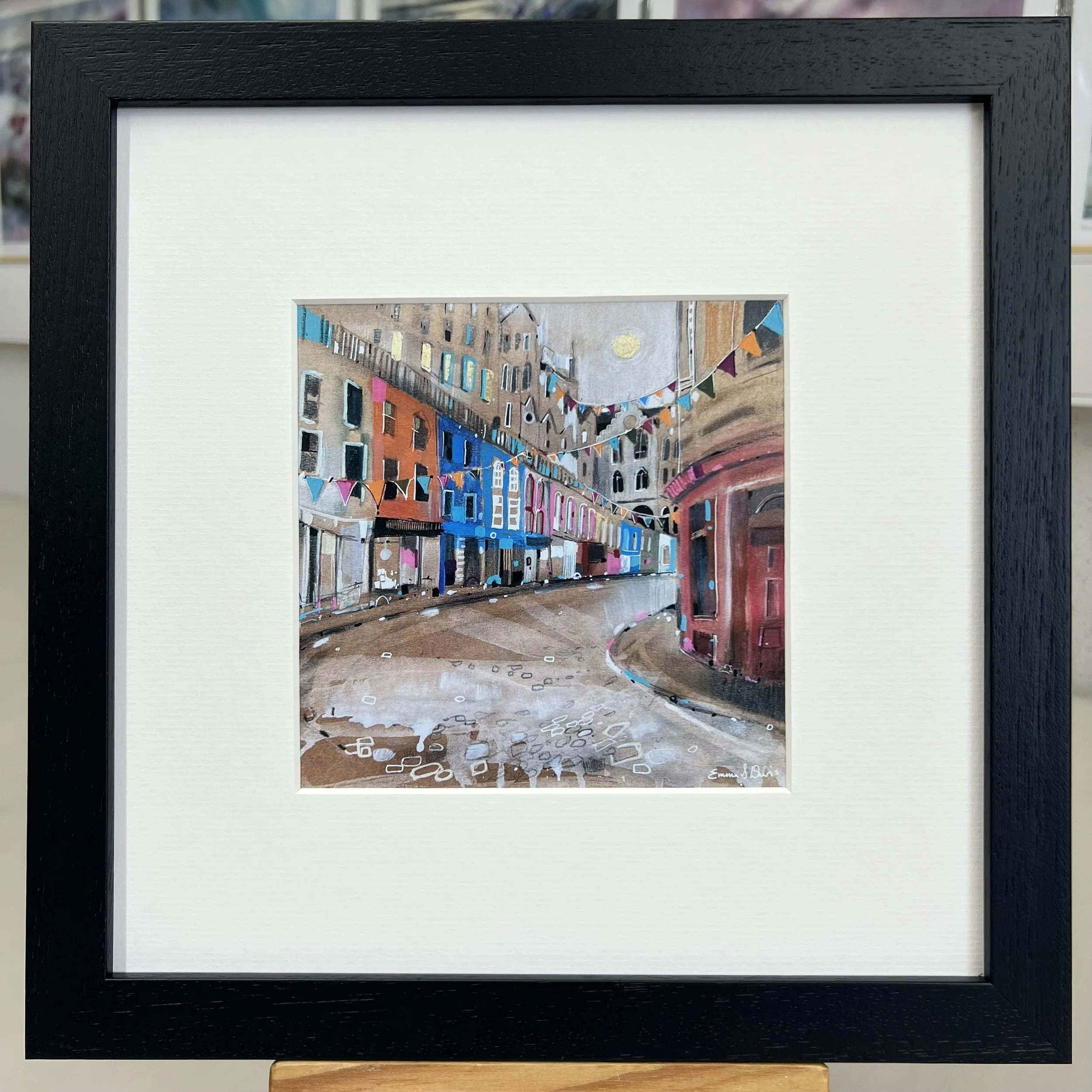 Bunting Victoria Street Edinburgh framed art card featuring colourful bunting and the famous curved street in Edinburgh, Scotland. Framed black single mount.