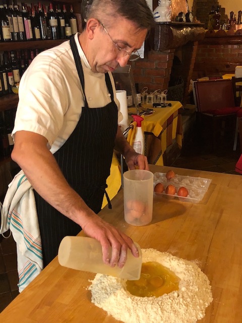 carefully pouring eggs into the flour well for pasta