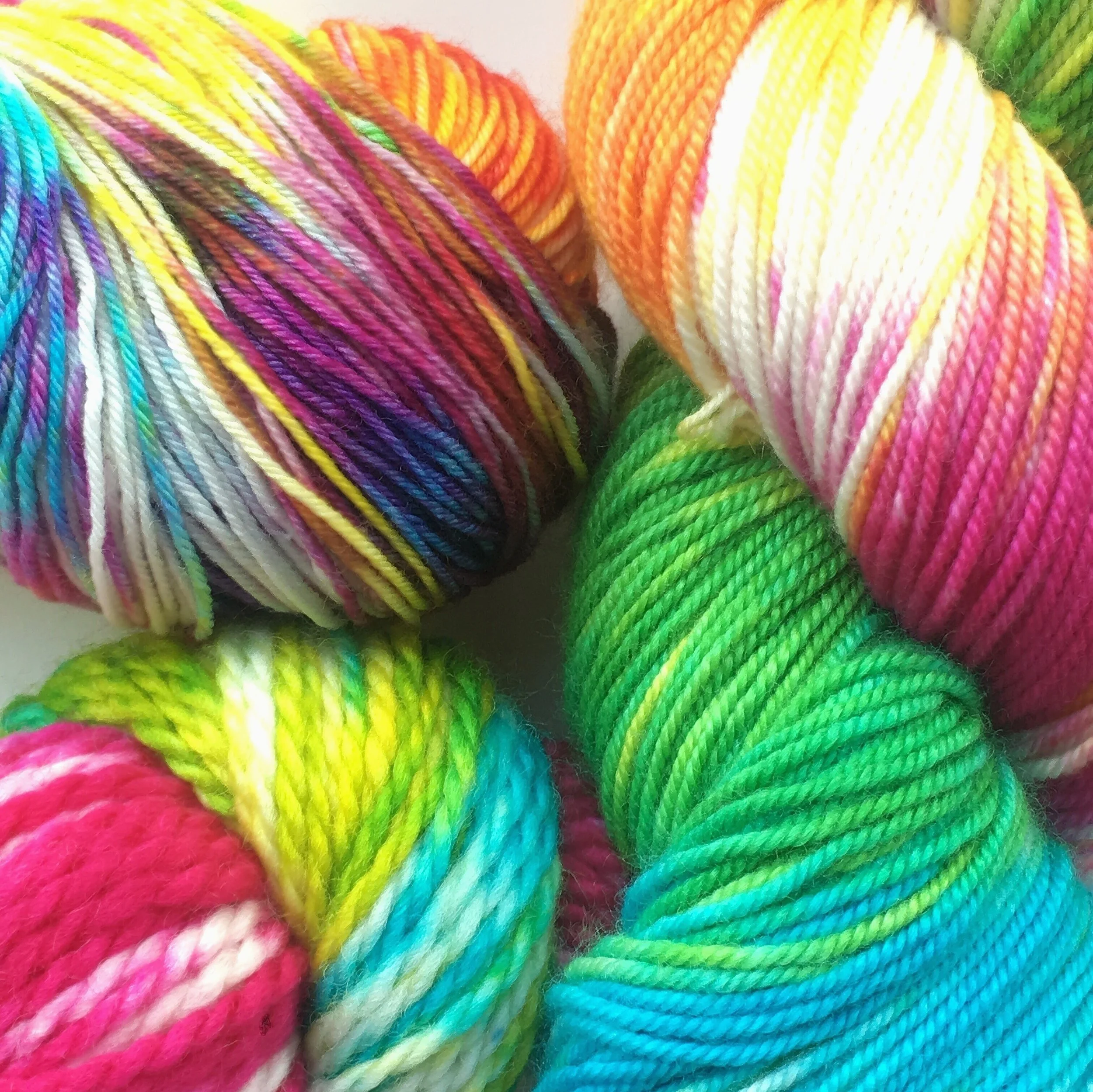 Taste the Rainbow Bright rainbow colors from fuchsia, orange, bright yellow, lime green, teal, and purple. Shown on Sheepy Feet, Silky Merino Sport, and BFL Aran.