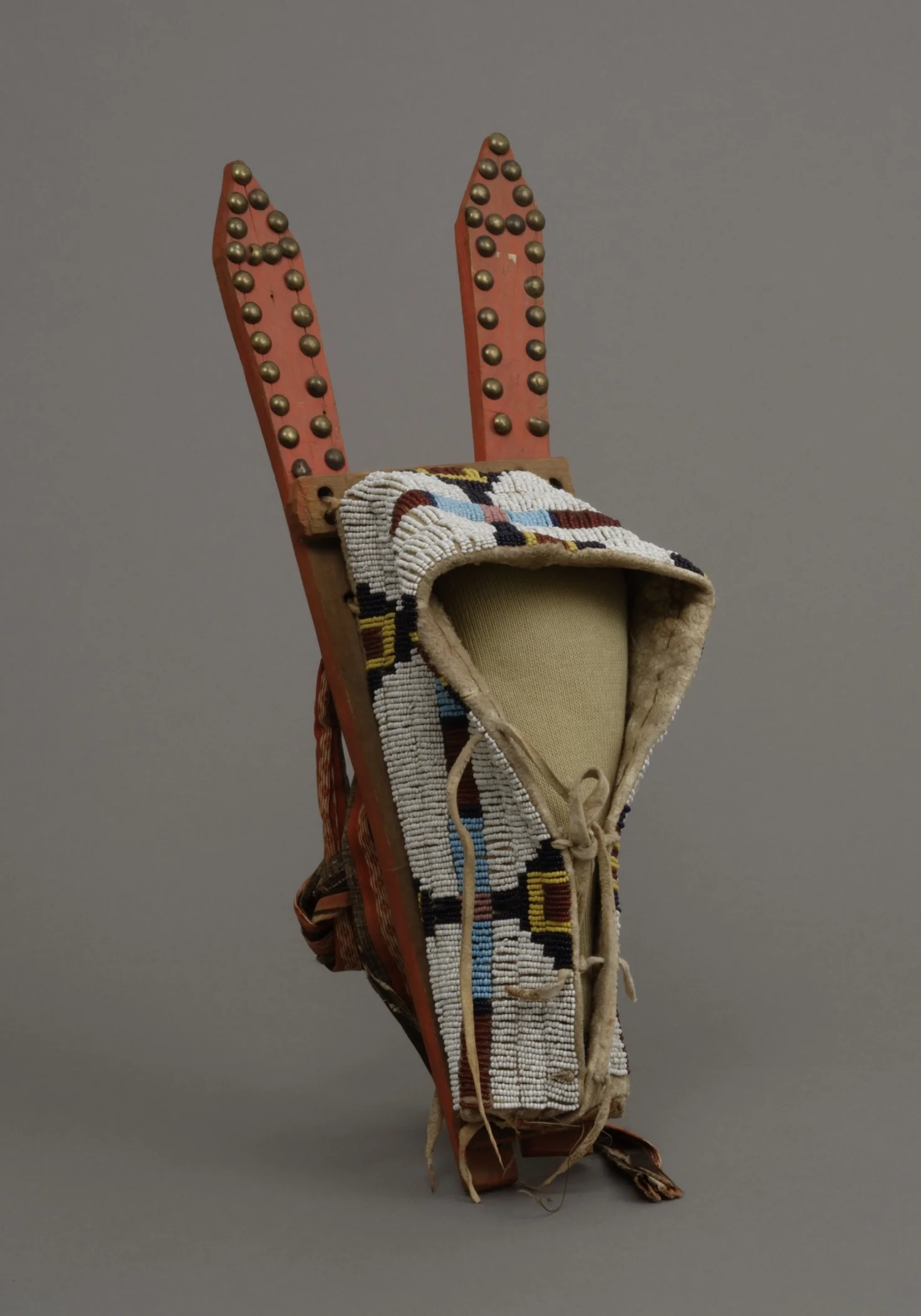 Tsistsistas / Suhtai (Cheyenne), toy cradleboard for a doll, about 1870. Wood, glass beads, hide, brass tacks, cotton cloth, paint, sinew, and thread, 4 3/4 × 16 1/4 × 5 1/2 in. Hood Museum of Art, Dartmouth College: Gift of Mrs. William M. Leeds; 1…