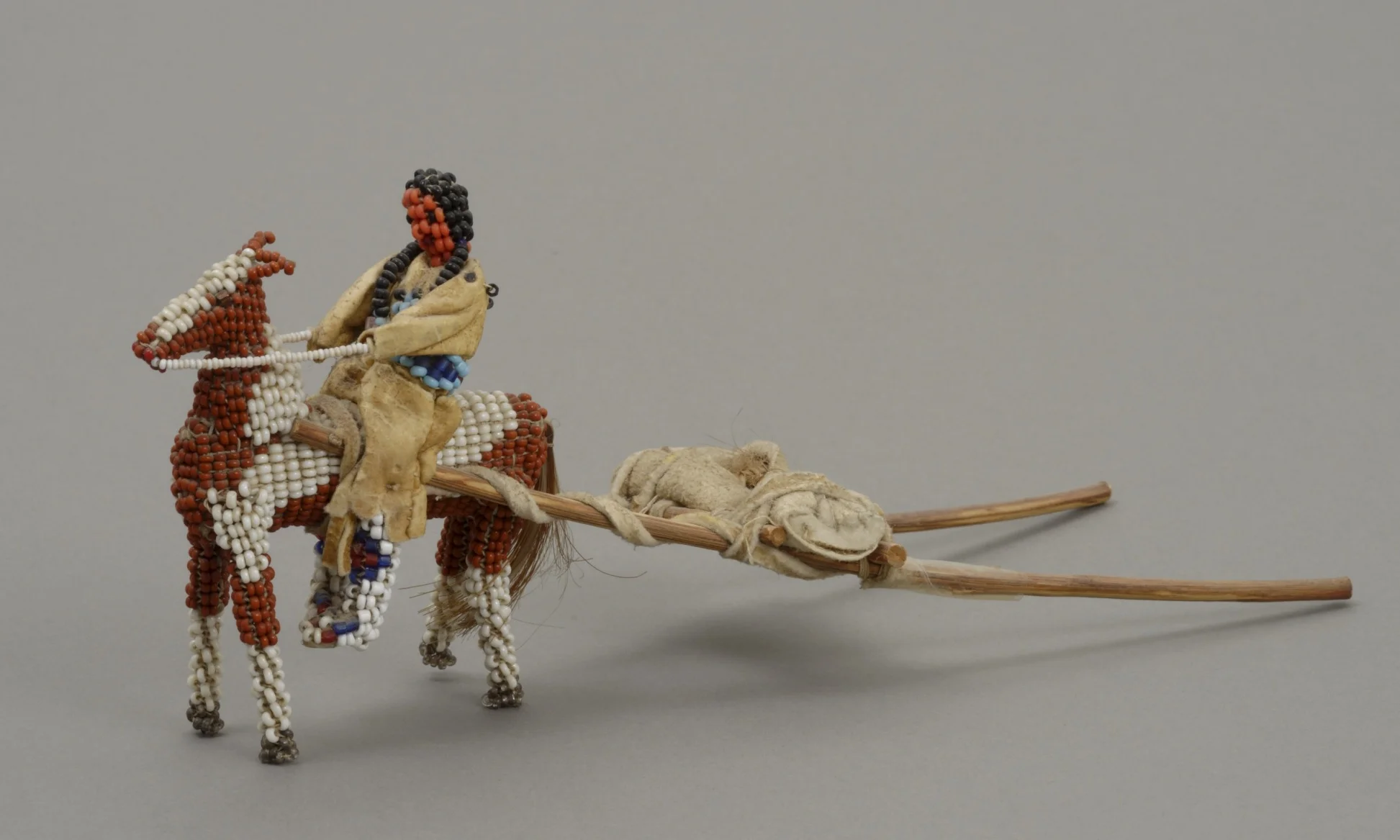 Lena Brown, American (Inunaina), born 1892 , doll representing an Inunaina woman, child, and horse, 1946. Glass trade beads, buckskin, horsehair, wood poles, string, and metal wire, 3 3/16 × 2 7/16 × 7 7/8 in. Hood Museum of Art, Dartmouth College: The Wellington Indian Doll Collection, Gift of Barbara Wellington Wells; 987.35.26800.