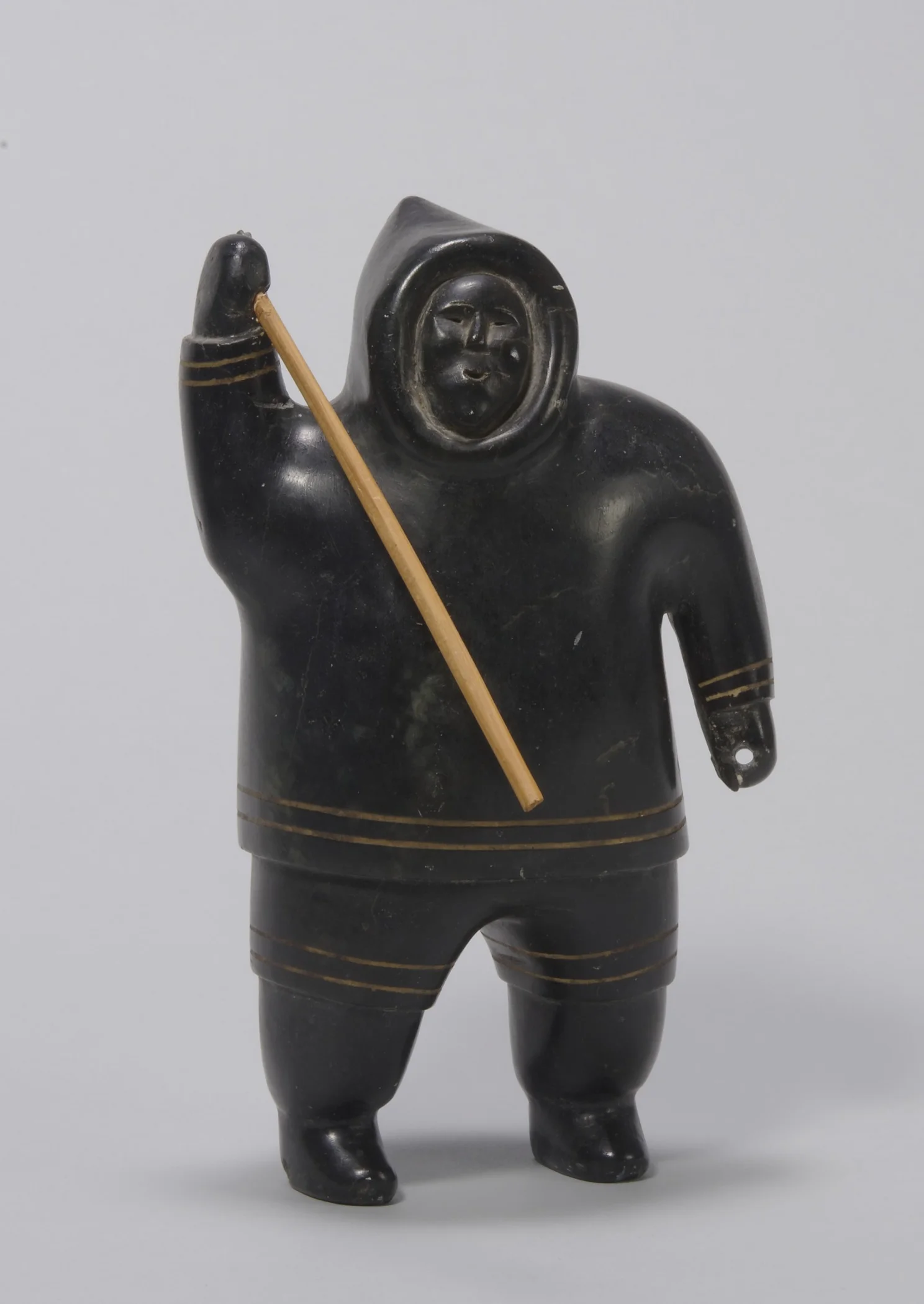 Akeeaktashuk, Canadian (Inuit), 1898–1954, Man in Parka Holding a Spear , about 1952. Serpentine, darkened with shoe polish, with plastic inlay, 8 3/4 × 5 1/8 × 2 15/16 in. Hood Museum of Art, Dartmouth College: Bequest of Evelyn Stefansson Nef; 2014.17.11.