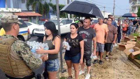 A Coast Guard member deployed to Borinquen, Puerto Rico in support of Hurricane Maria relief efforts delivers a case of water to a resident of Moca, Puerto Rico, Oct. 9, 2017. Photo by David Micallef.