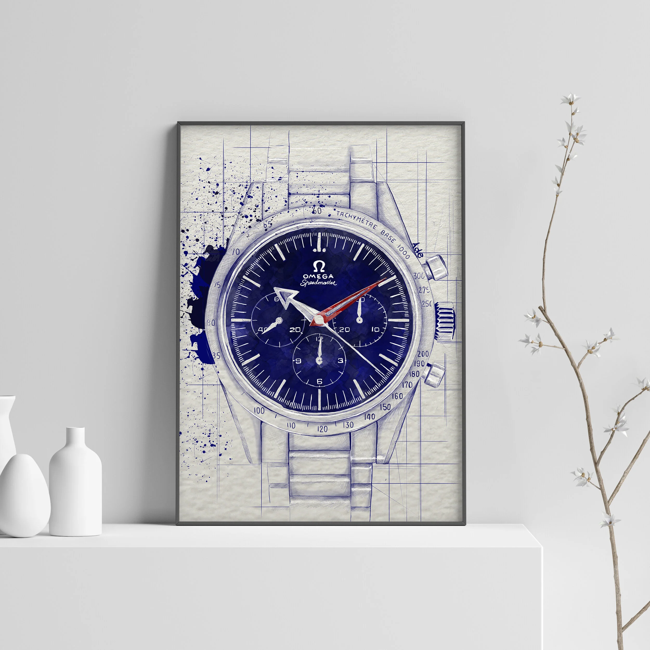 A framed poster of a blue Omega Speedmaster watch design sketch on a white wall, with two white vases and a branch with white flowers on a white shelf.