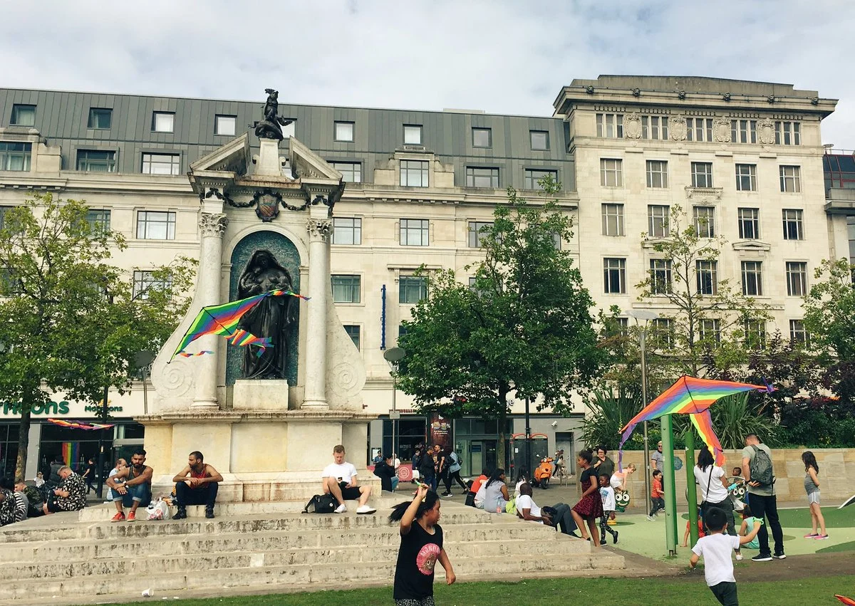 Some kids enjoying the Flying for freedom rainbow kite intervention in Piccadilly gardens