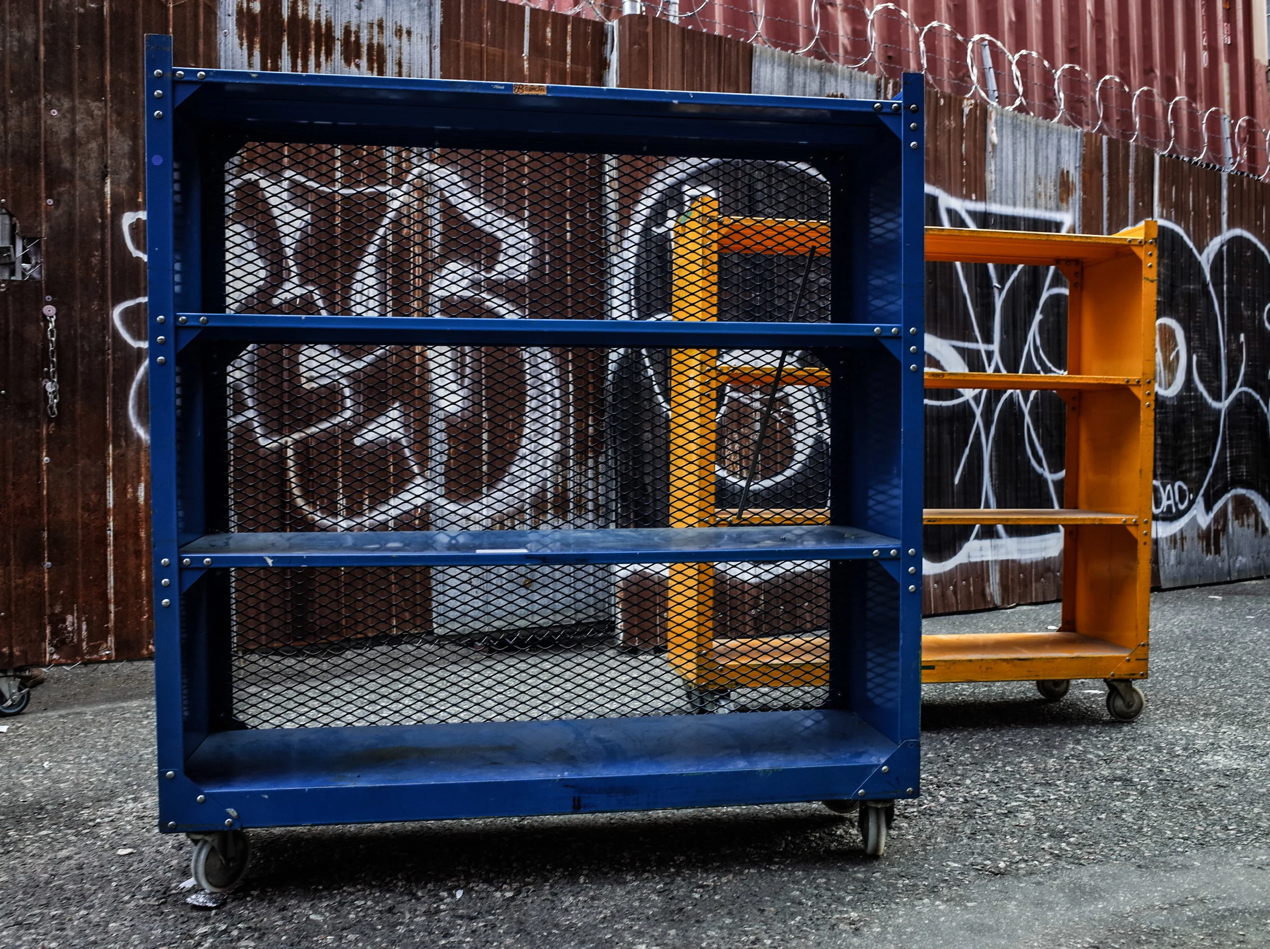 Colorful industrial steel shelving units on wheels against a graffiti wall at Space Lab Vancouver, linking to the vintage furniture page.
