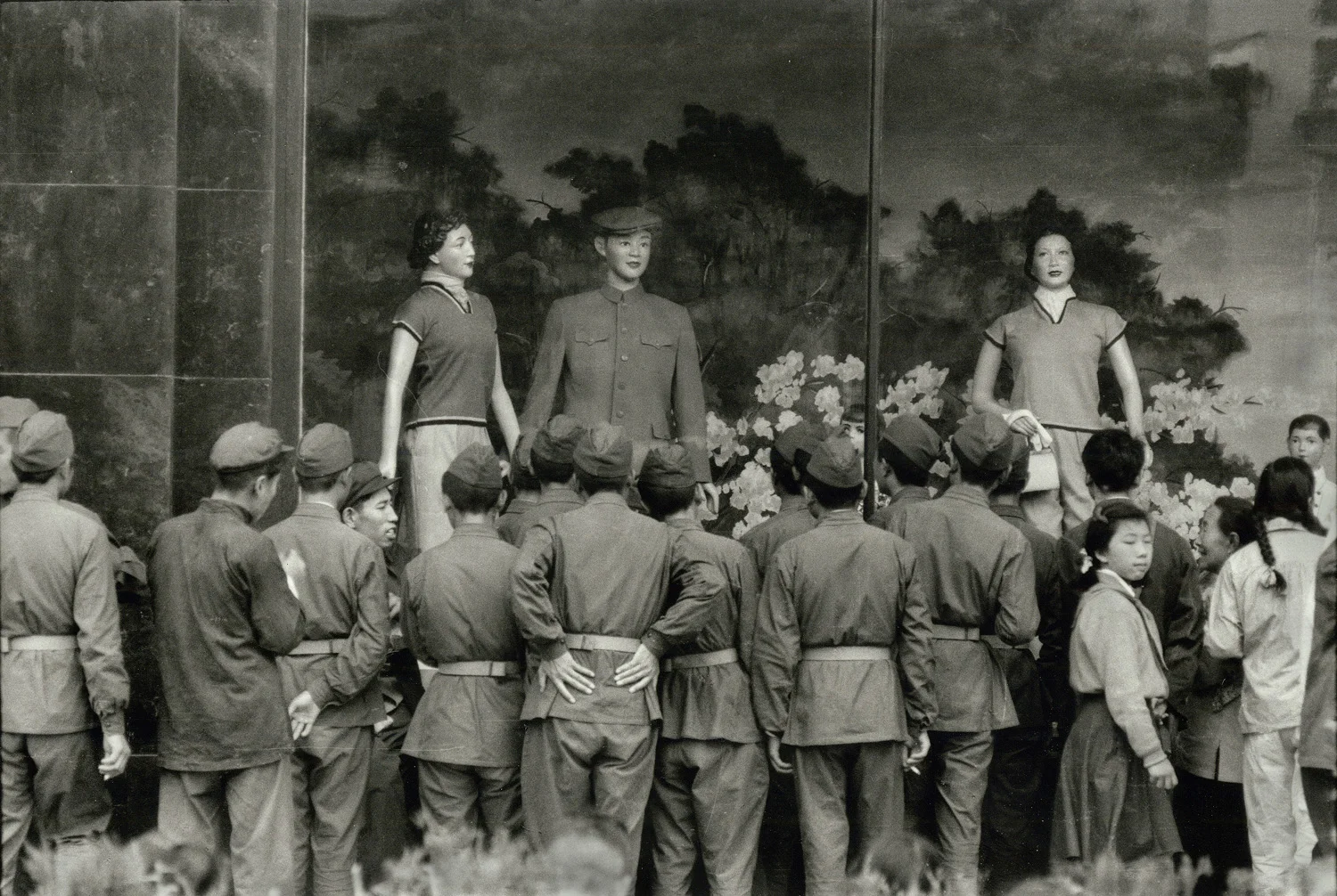 Soldiers looking at a "Dress Reform" display of "Western fashions" in the window of a new department store in Wang Fu Chin, Peking. China. 1956. (RDH C014-12)