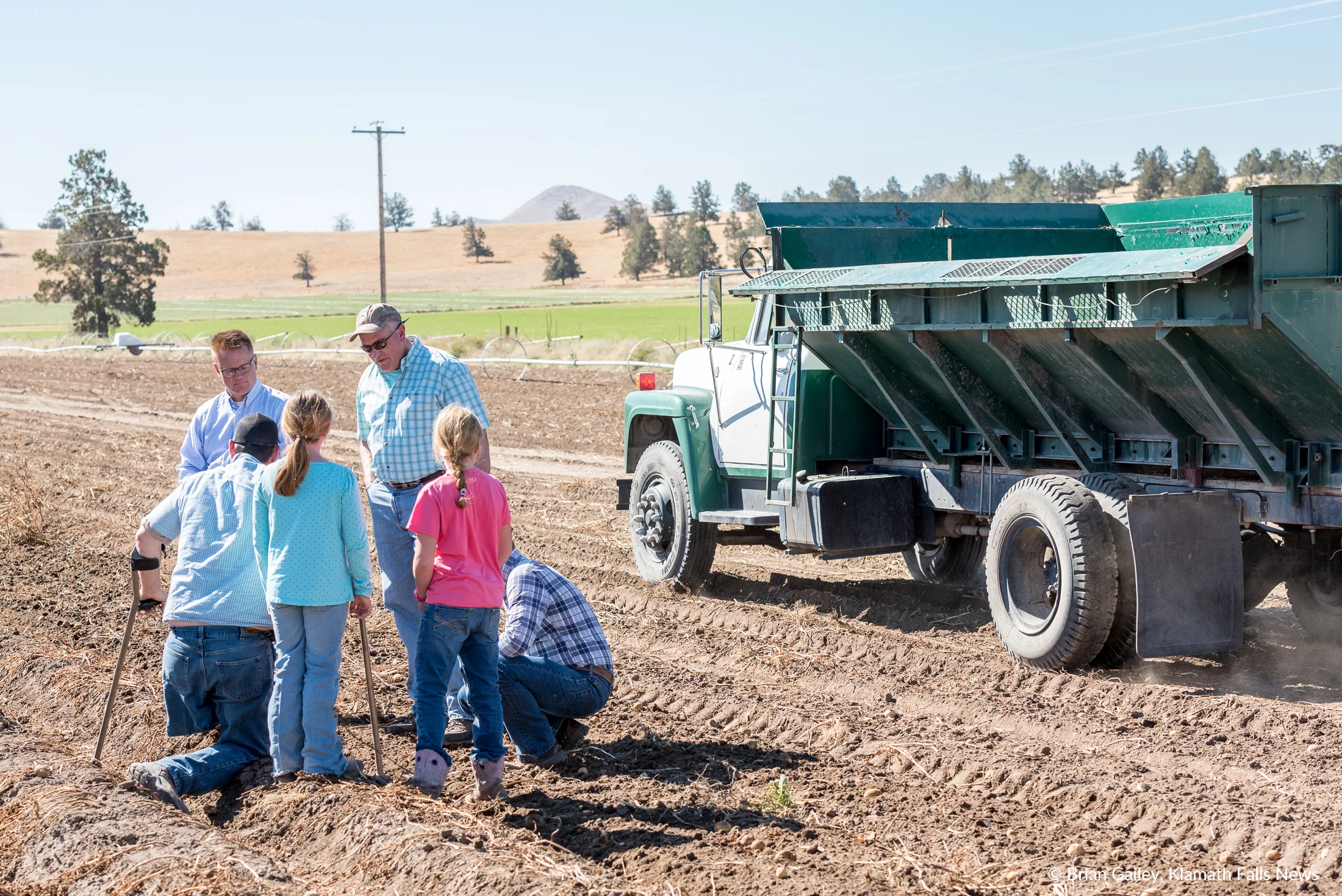 Local farmers and guests of the Harvest Tour check the ground where a potato harvester had just worked the soil. (Brian Gailey)
