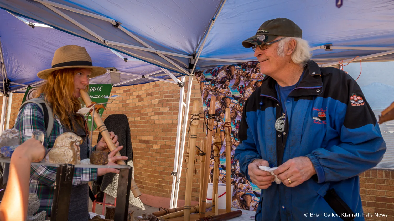 A young woman tries out hand made flutes at the Klamath Falls Farmers' Market. June 30, 2018 (Brian Gailey)