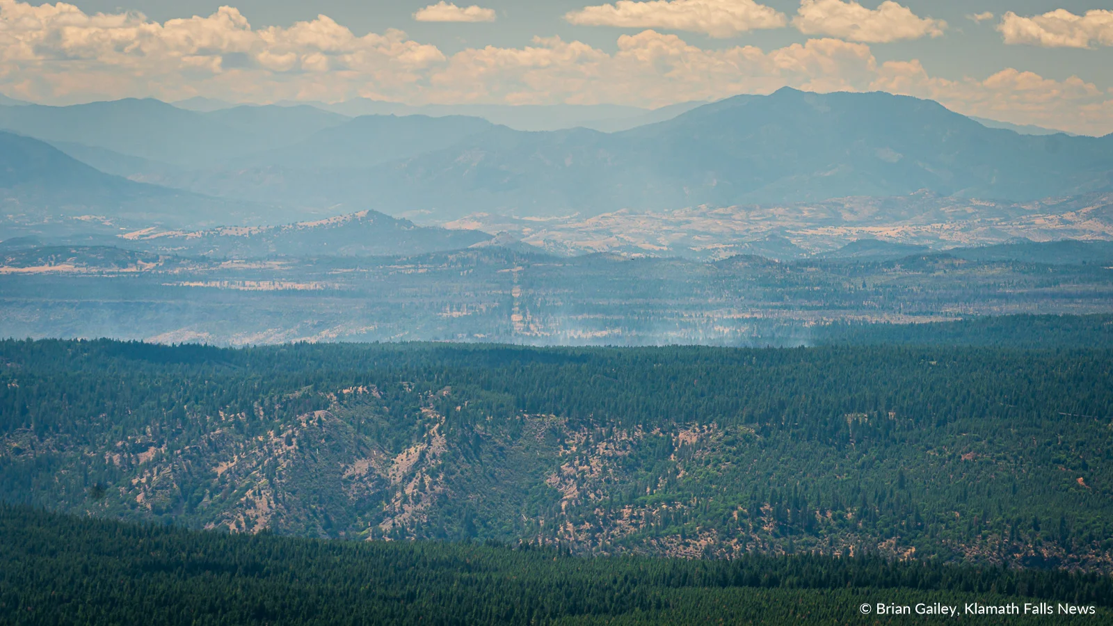 A thin layer of smoke from the #WardFire rises from the forest in southwestern Klamath County. Calm weather and cooler temperatures along with recent rains have helped keep the Ward Fires impacts minimal. August 11, 2019. (Image, Brian Gailey / Klamath Falls News)