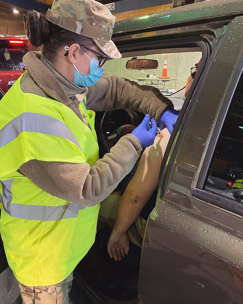 U.S. Air Force Tech. Sgt. Meghan Olson, 173rd Fighter Wing, administers a COVID-19 vaccination during a drive through COVID-19 vaccine clinic in Medford, Oregon January 22, 2021. Twelve Airmen from Kingsley Field are on State Active Duty as part of Task Force Guardian supporting COVID-19 vaccine clinics in Southern Oregon. (U.S. Air National Guard Courtesy photo)