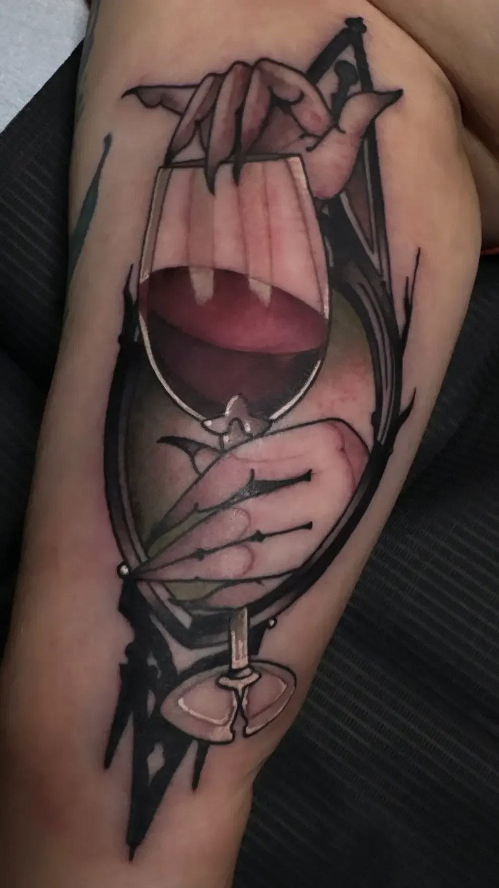 Gia Rose tattoo: clawed hands holding a wine glass of deep red, framed in black filigree