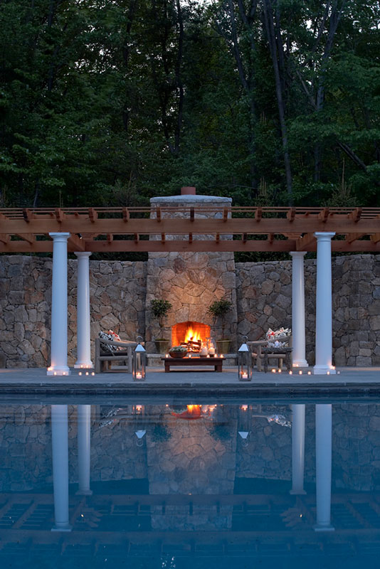 Poolside outdoor fireplace at night