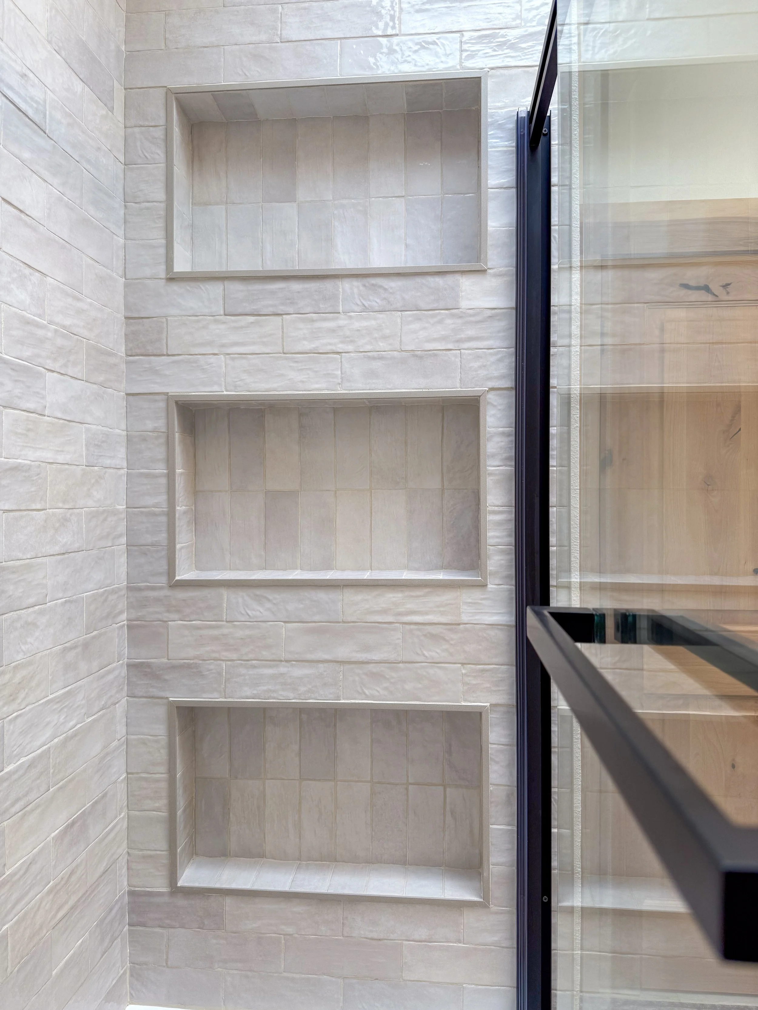 primary bathroom remodel, earthy bathroom inspiration, shower and bathtub combo, shower system with handheld sprayer, double vanity, wood vanity, floating shelves, arched medicine cabinets, toilet paper niche, double light sconce, brass finishes