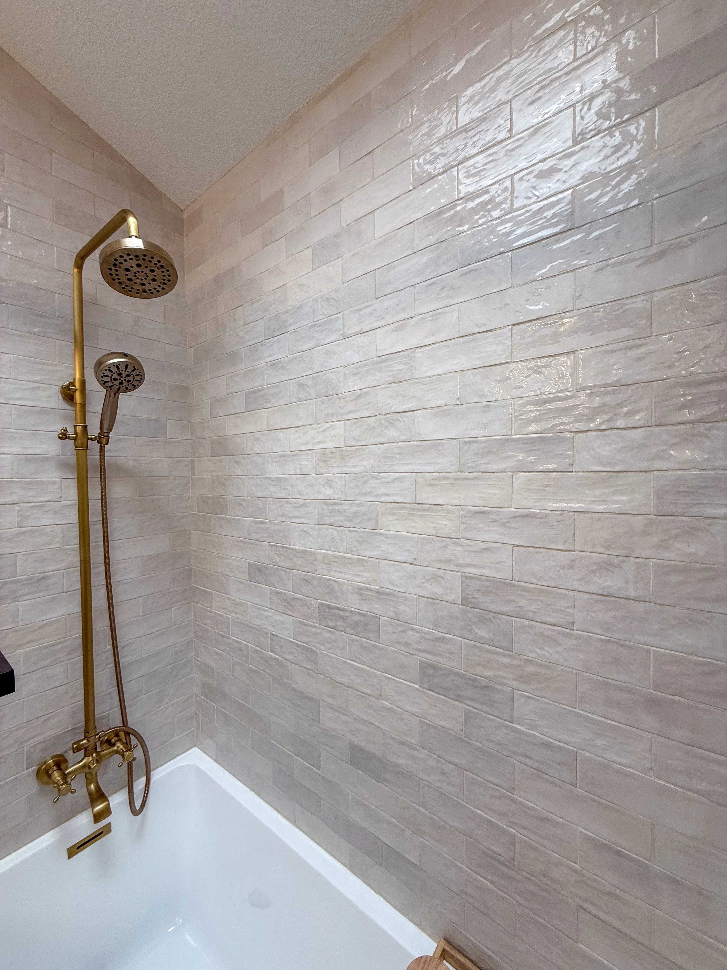 primary bathroom remodel, earthy bathroom inspiration, shower and bathtub combo, shower system with handheld sprayer, double vanity, wood vanity, floating shelves, arched medicine cabinets, toilet paper niche, double light sconce, brass finishes