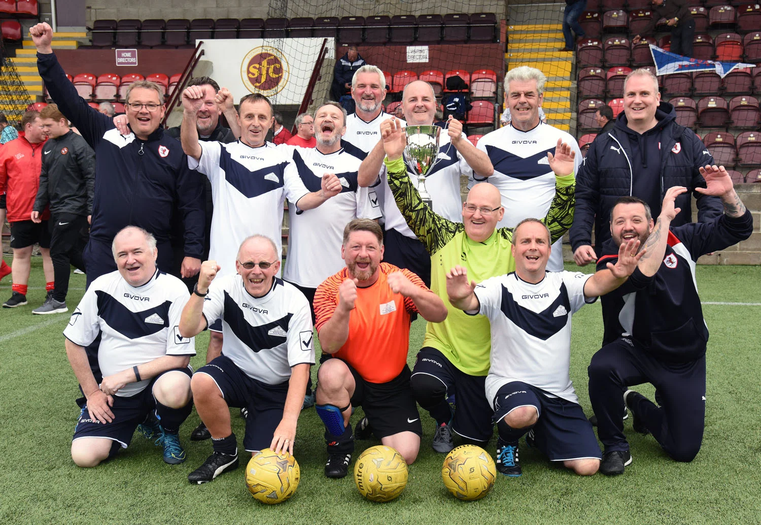 Raith Rovers team and coaches celebrate after receiving the Trophy from Walking Football Scotland Chairman Gary McLaughlin