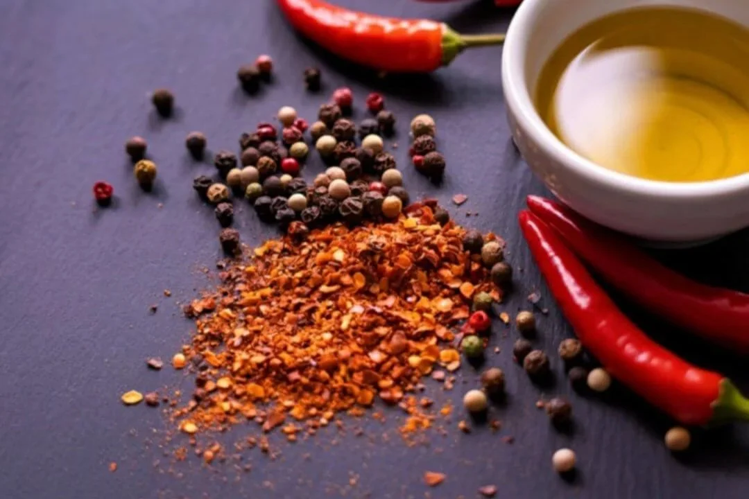 Hot peppers, chilis and peppercorns on a dark wood table.