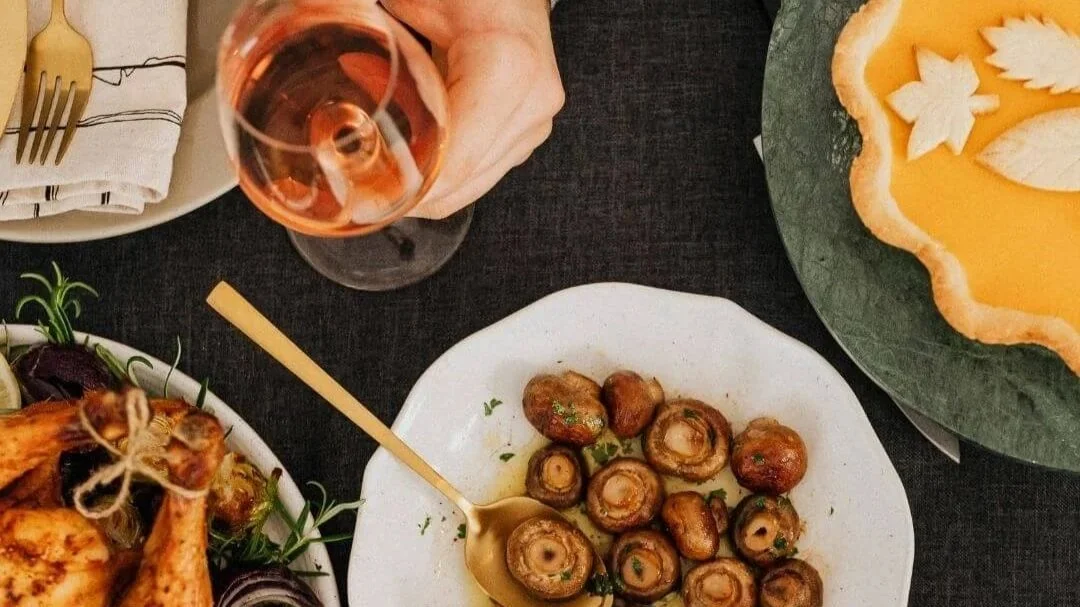 Plan view of someone with a wine glass enjoying a fall themed meal.