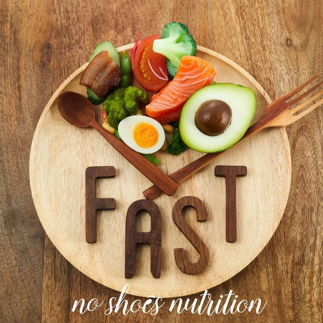 Wooden plate on a wood table with veggies and healthy protein from 10-2pm and the spoon and fork acting as clock hands to indicate no food for the rest of the day.