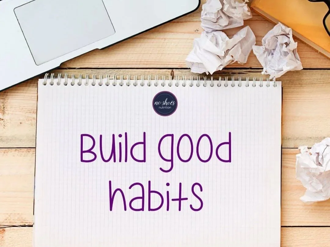 Laptop, note pad and crumpled paper beside a Build Good Habits note to self.