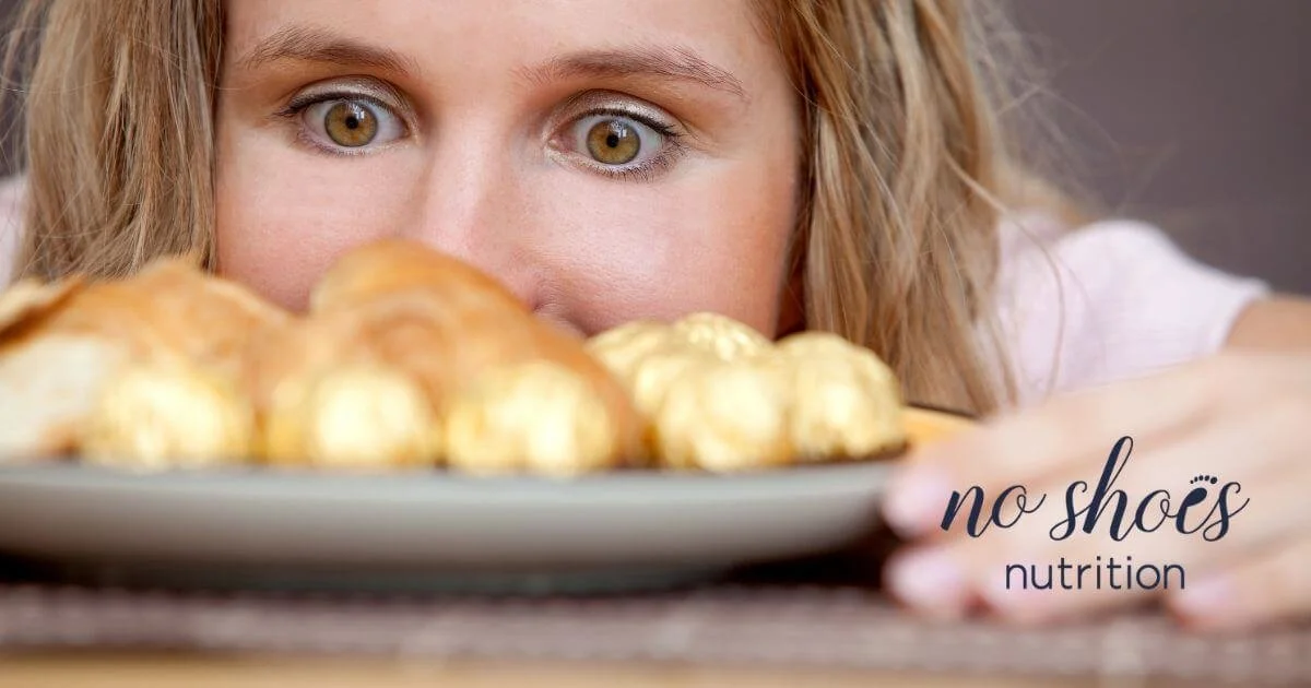Blonde woman looking longingly at a plate of treats she is craving.