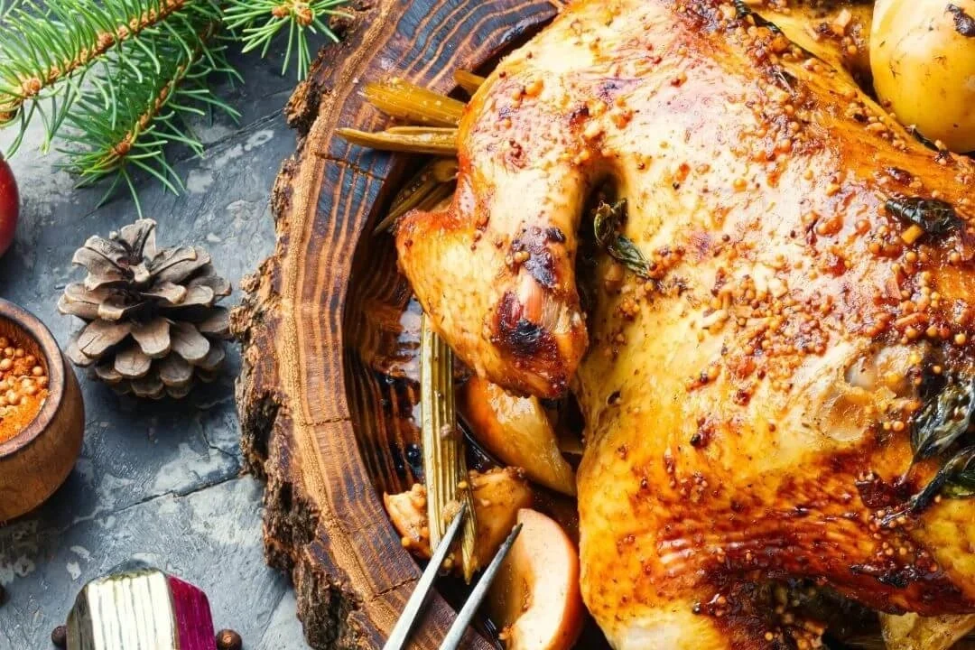 Turkey dinner on a wooden platter with pine and pine cones.