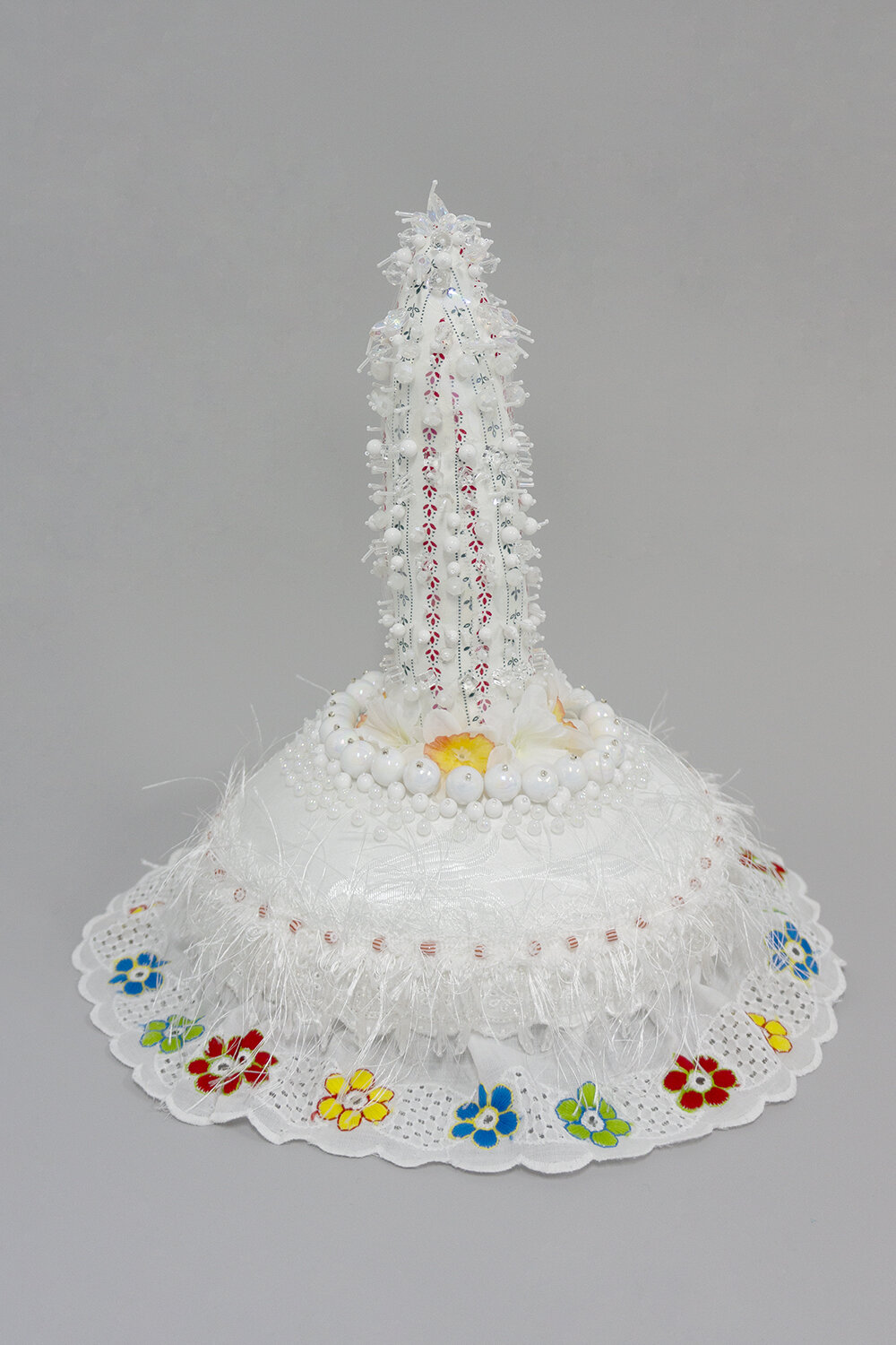   Butter , 2019, Crystal and plastic beads, found fabric, trim, fabric flower, polyester batting, thread, glass stand, 16 x 11 x 11” 