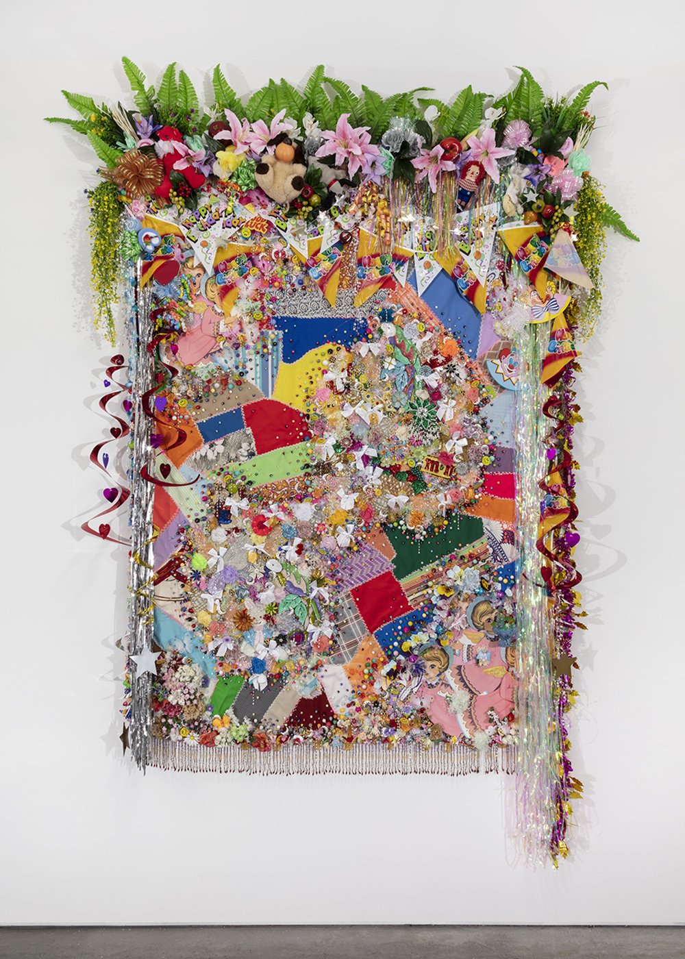  Shroud #2,  2022, Found ‘Crazy’ quilt ca. 1950, trim, fabric flowers, streamers, banners, garland, paper cut-outs, toys, ribbon, costume jewelry, buttons, plastic flowers, fauna, and fruit, beads, sequins, thread, fabric, Douglas fir, 110 x 82 x 10