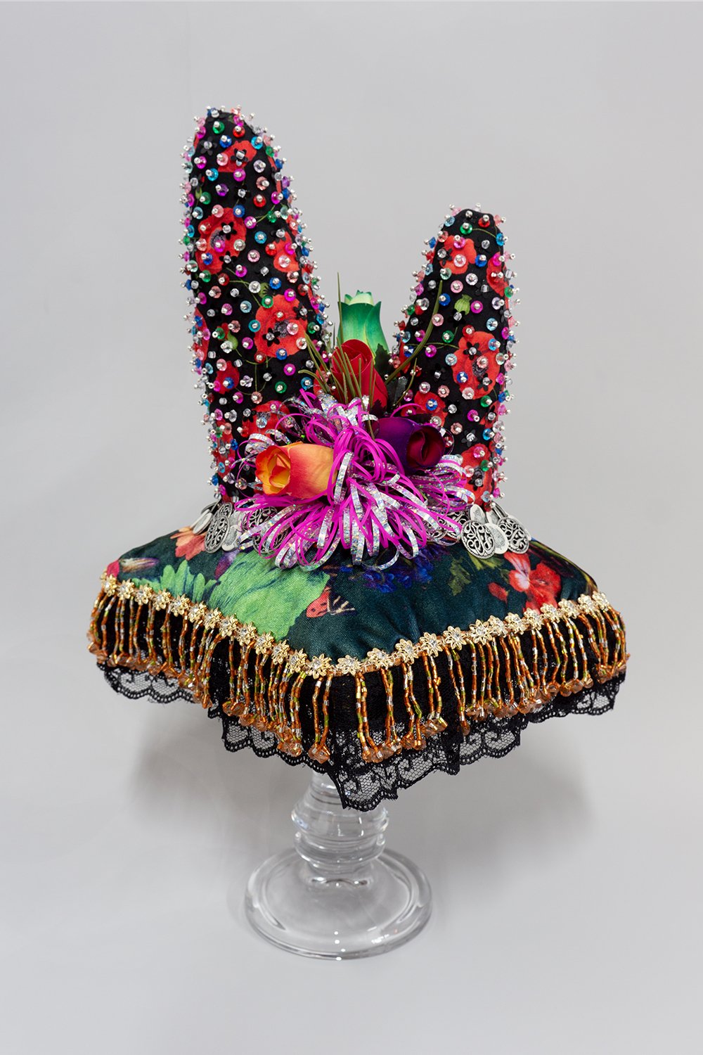   Untitled,  2024, Plastic beads, found fabric, trim, wood and plastic flowers, buttons, ribbon, polyester batting, thread, glass stand, 18.5 x 9 x 9” 